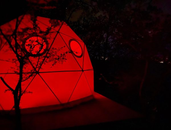 Dôme géodésique illuminé en rouge, niché dans la nature du Languedoc-Roussillon.