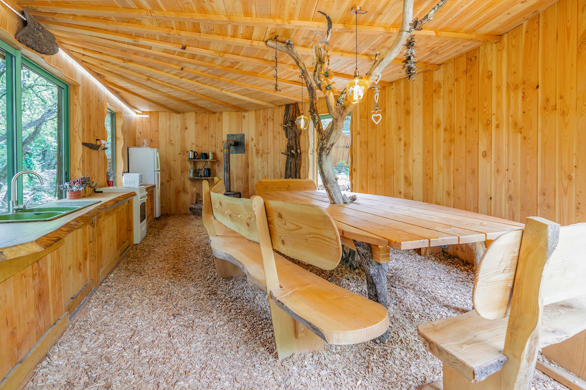 espace-cuisine-2000-1 Cabane en bois chaleureuse avec table en tronc darbre et décor naturel.