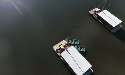 Bungalows flottants sur un lac, entourés de verdure luxuriante et deau calme.