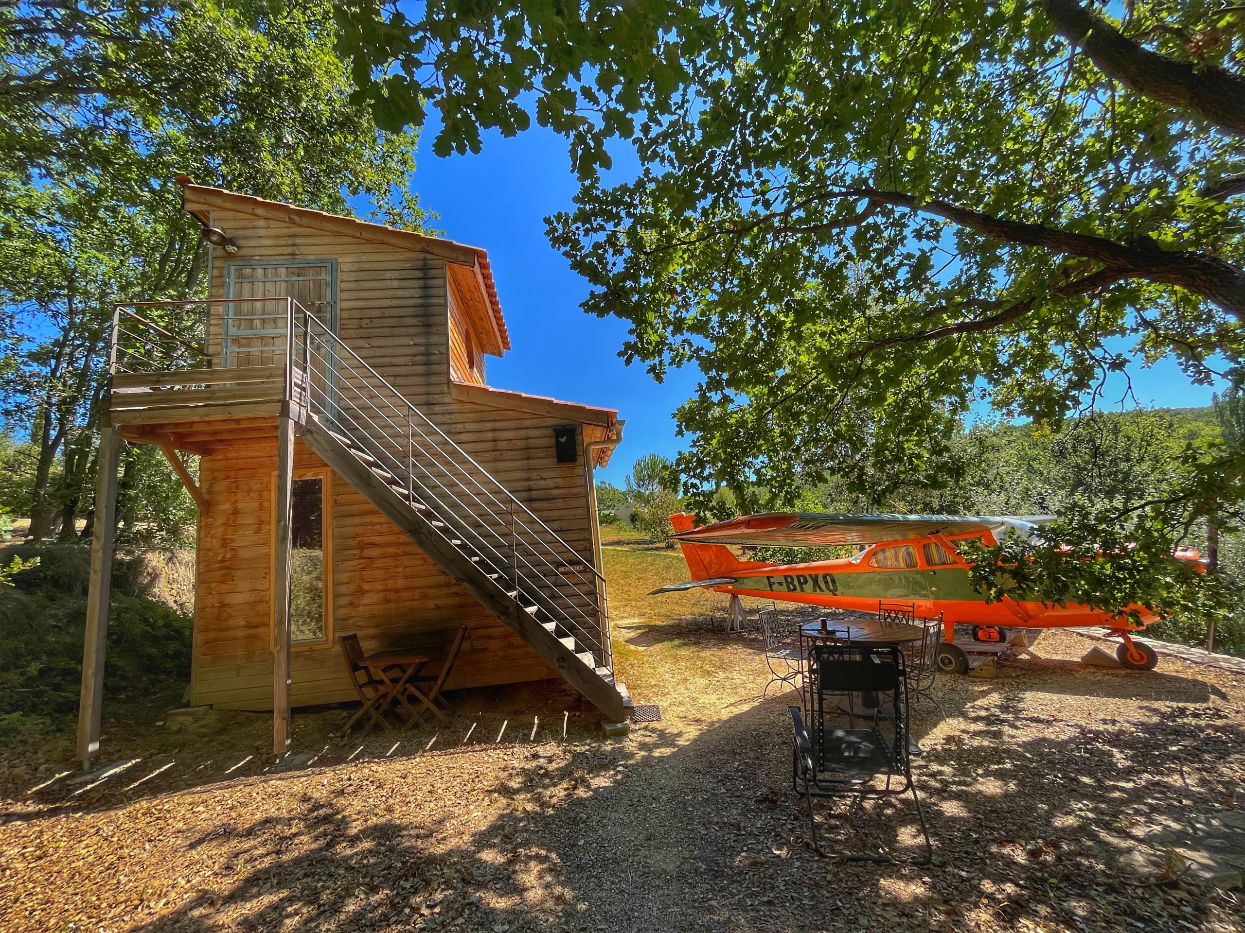 avion cessna a barjac 2 aout 2023 Cabane en bois avec un avion orange, entourée darbres au Languedoc-Roussillon.