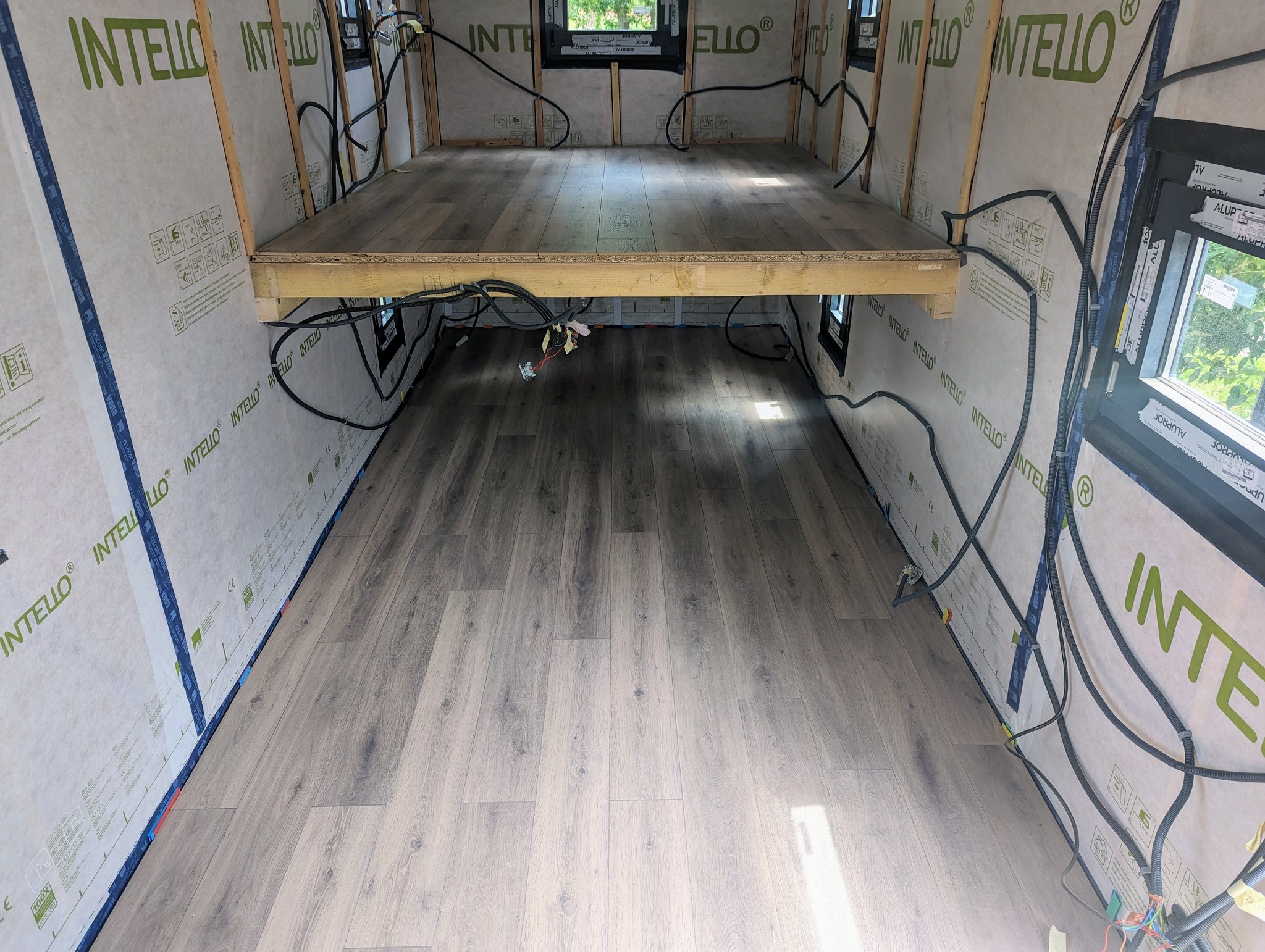 Hébergement touristique : intérieur dune cabane avec un sol en bois clair et des fenêtres.