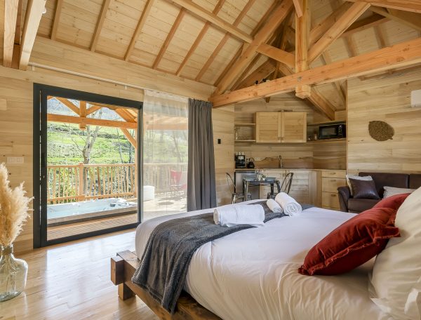 Chalet en bois avec vue sur la nature et jacuzzi sur la terrasse.