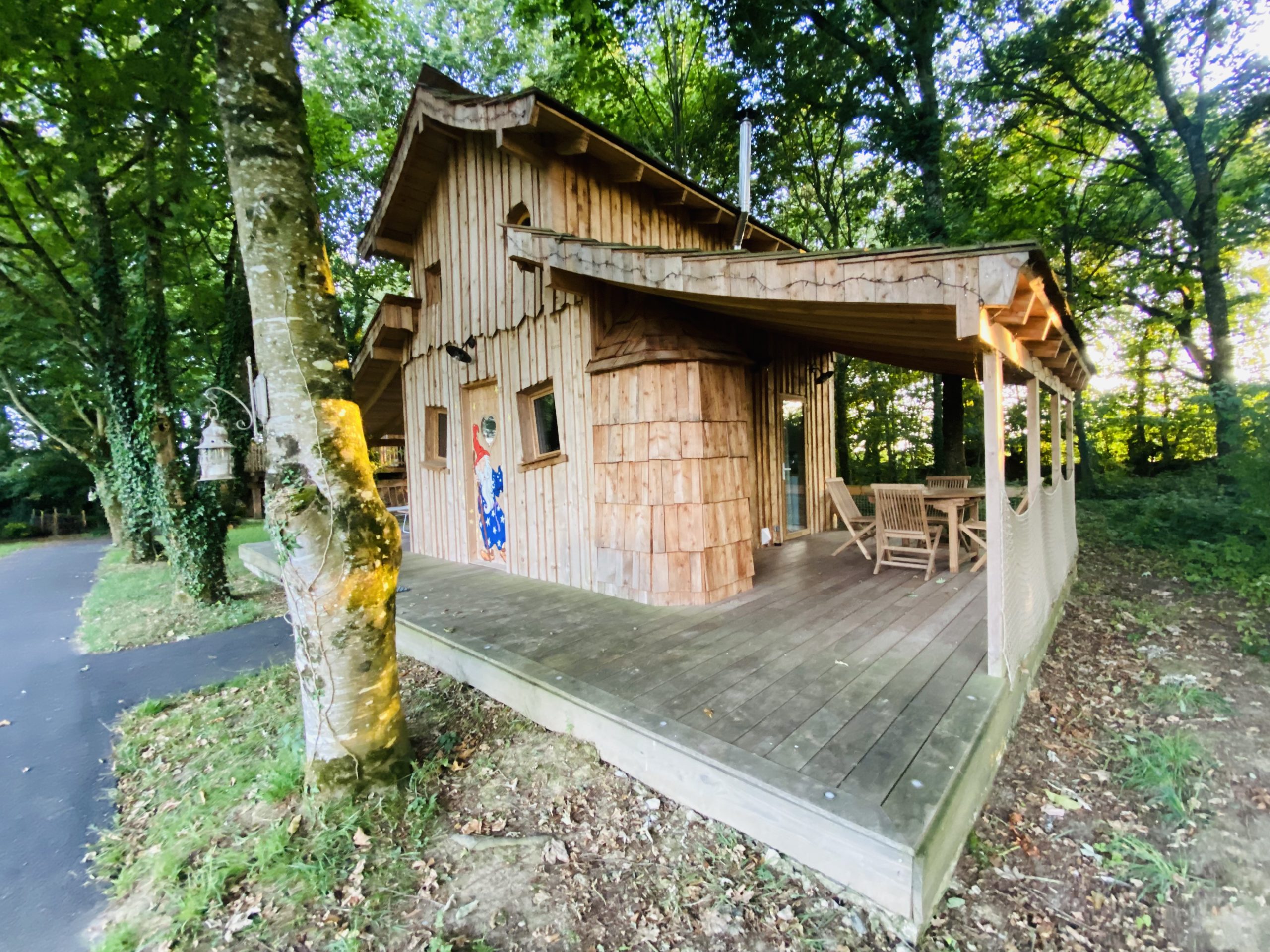 FullSizeRender-6 Cabane en bois en Bretagne, entourée darbres, avec terrasse en bois accueillante.