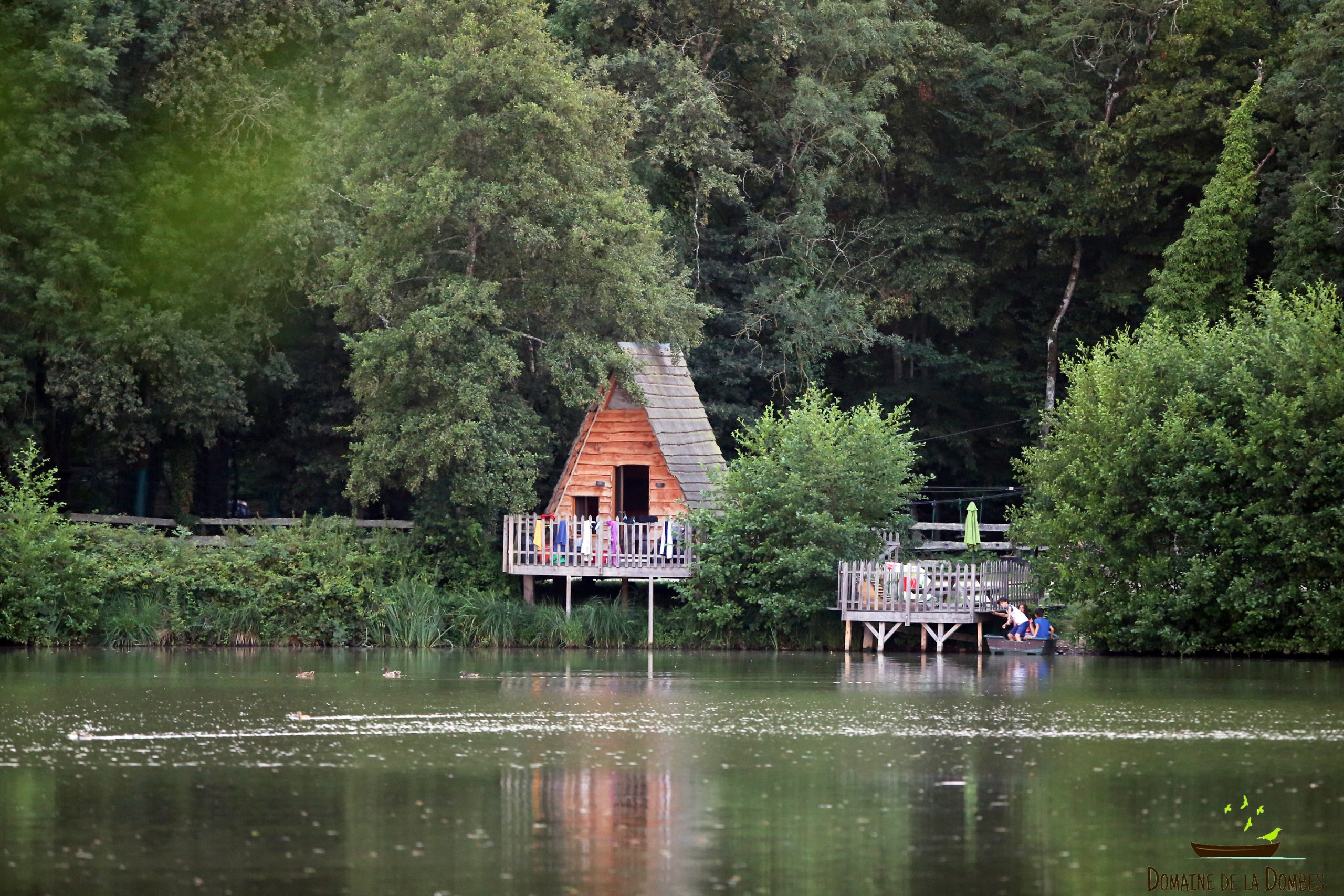 IMG_3324 Cabane en bois au bord dun lac, entourée de verdure luxuriante en Auvergne-Rhône-Alpes.