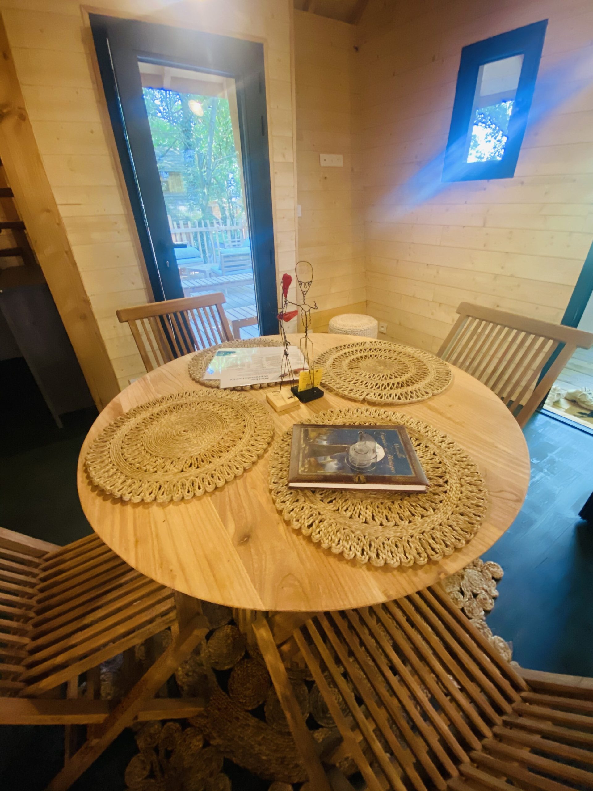 IMG_7839 Hébergement insolite en Bretagne : chalet en bois avec table ronde et chaises en rotin.