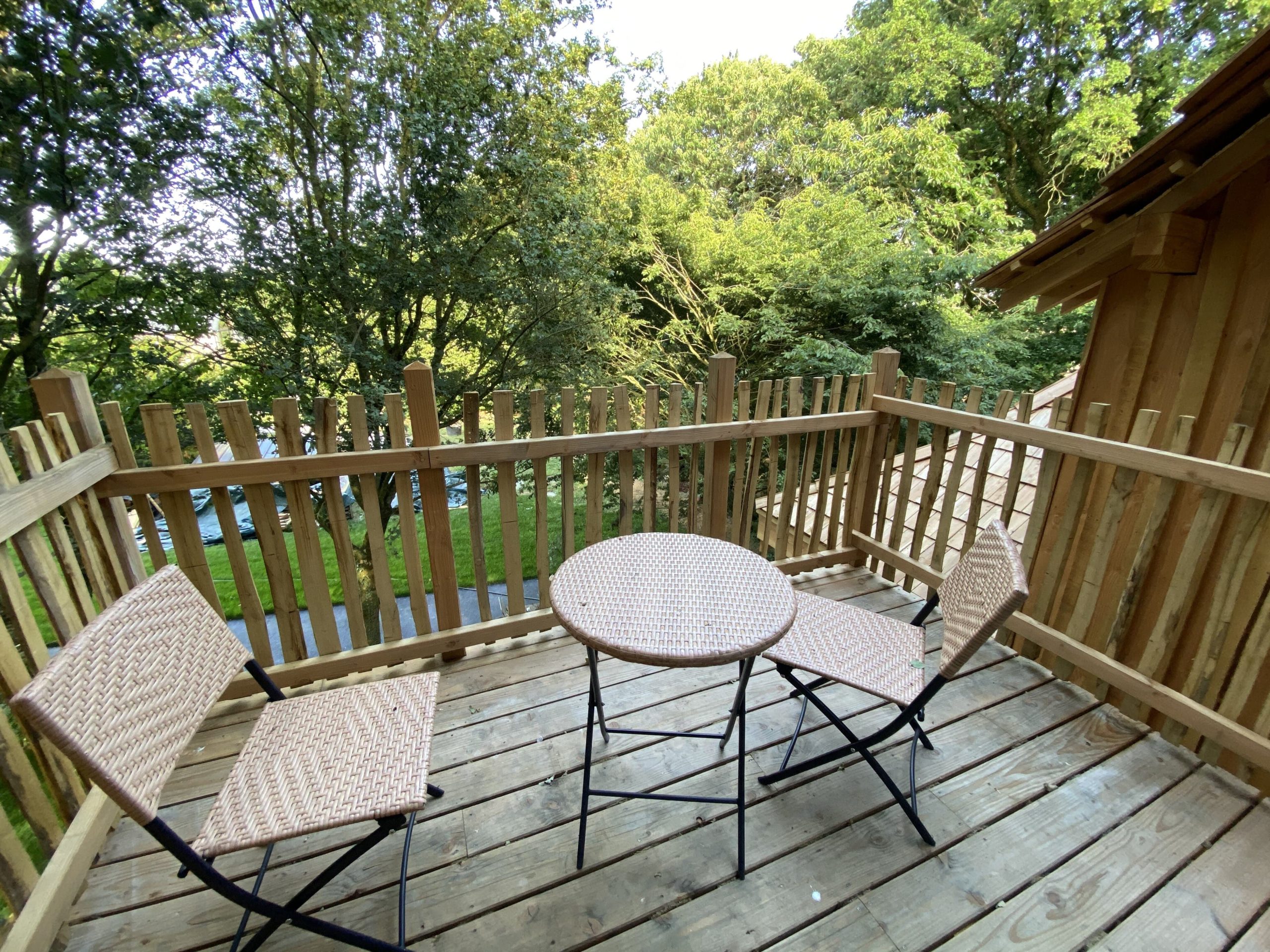 IMG_7850 Terrasse en bois avec deux chaises et une table, hébergement insolite en Bretagne.