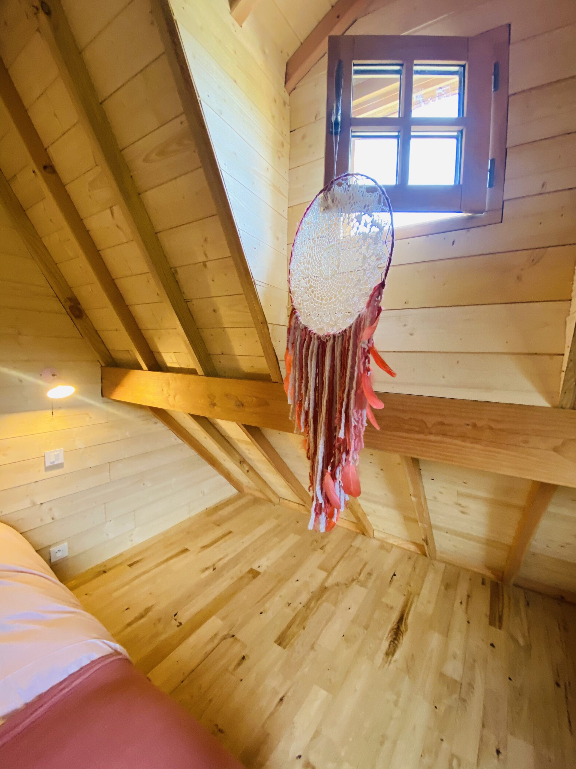 IMG_7893 Chalet en bois en Bretagne, avec un plafond en poutres et un attrape-rêves coloré.