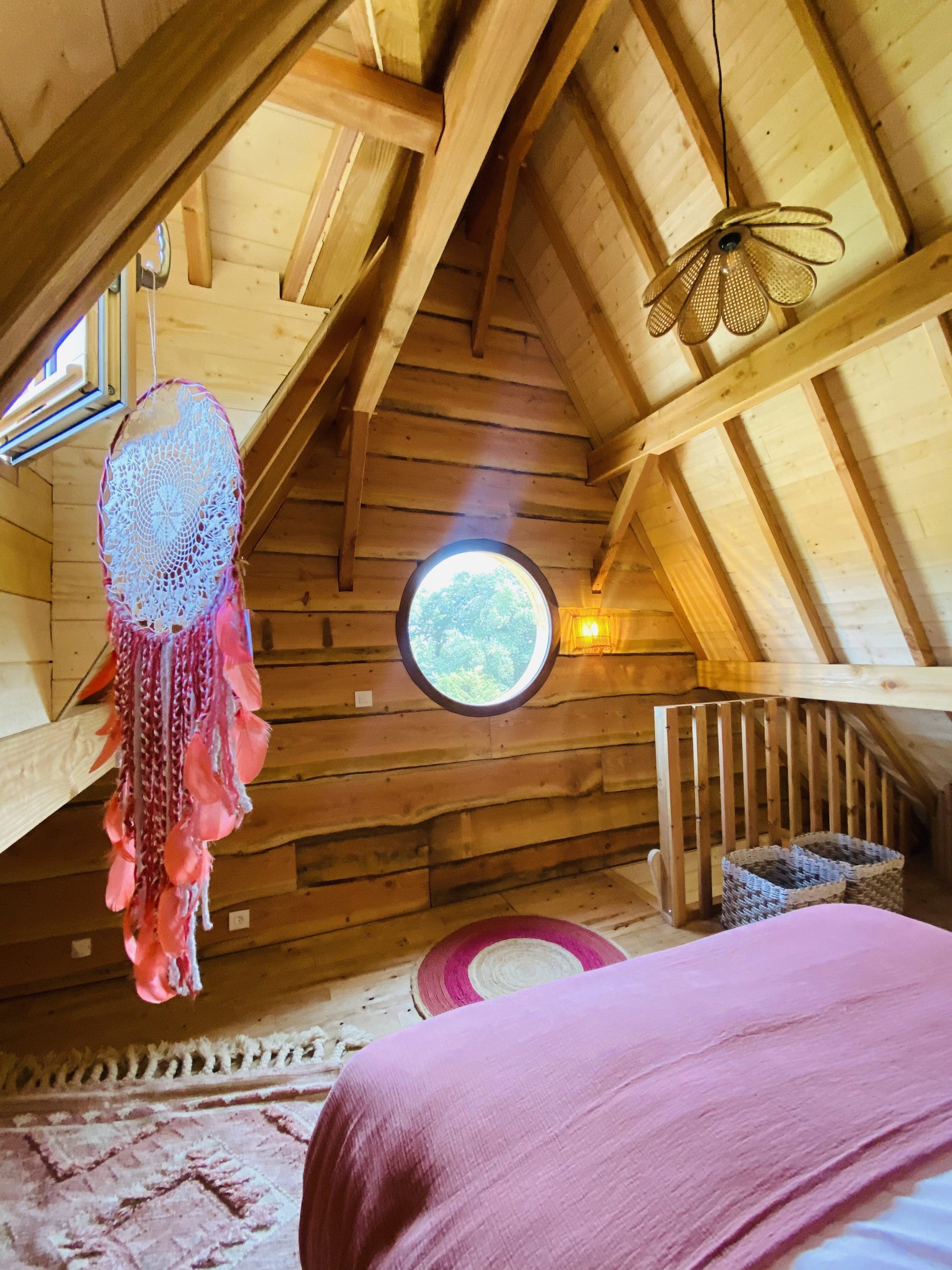 IMG_7905 Chalet en bois en Bretagne, avec un plafond en poutres et une fenêtre ronde.