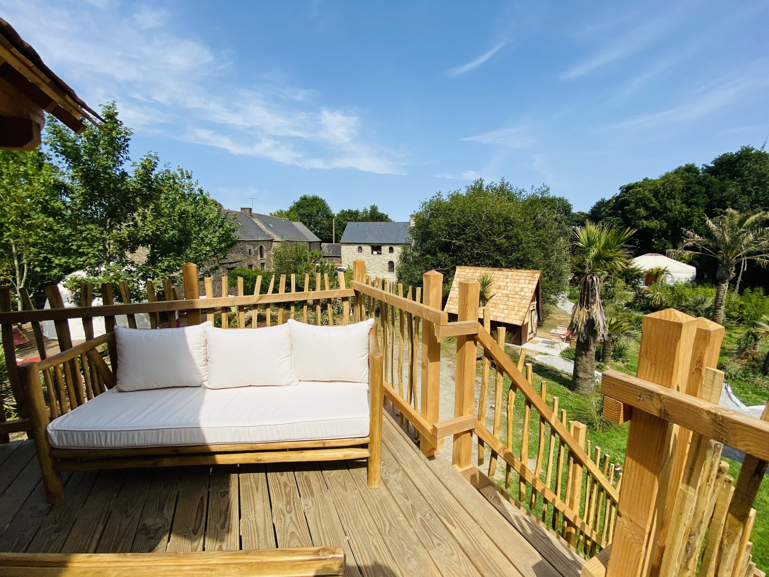 IMG_7924 Cabane perchée en Bretagne avec terrasse en bois et vue sur la verdure environnante.