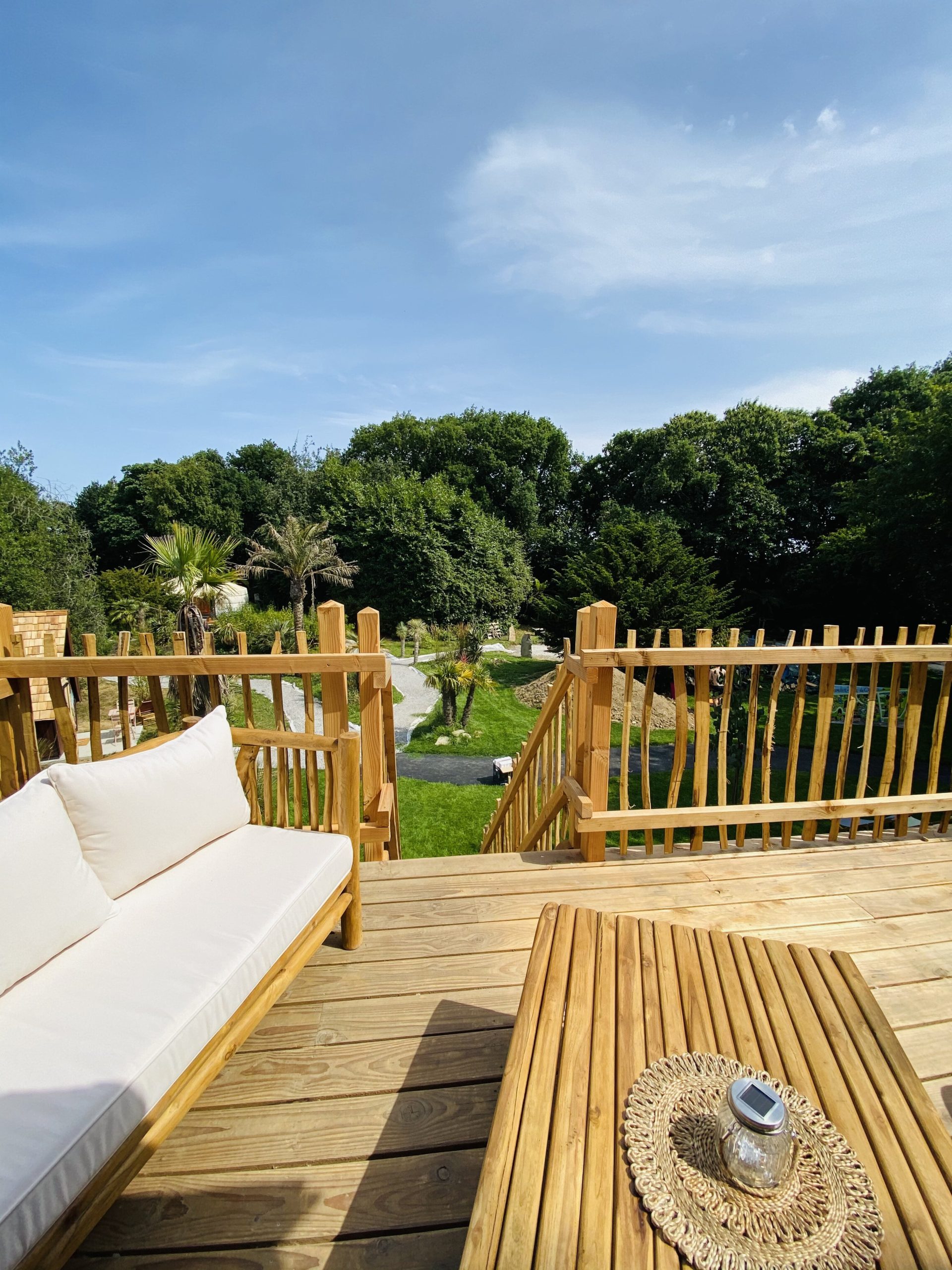 IMG_7925 Cabane en bois en Bretagne, avec vue sur un jardin verdoyant et des palmiers.