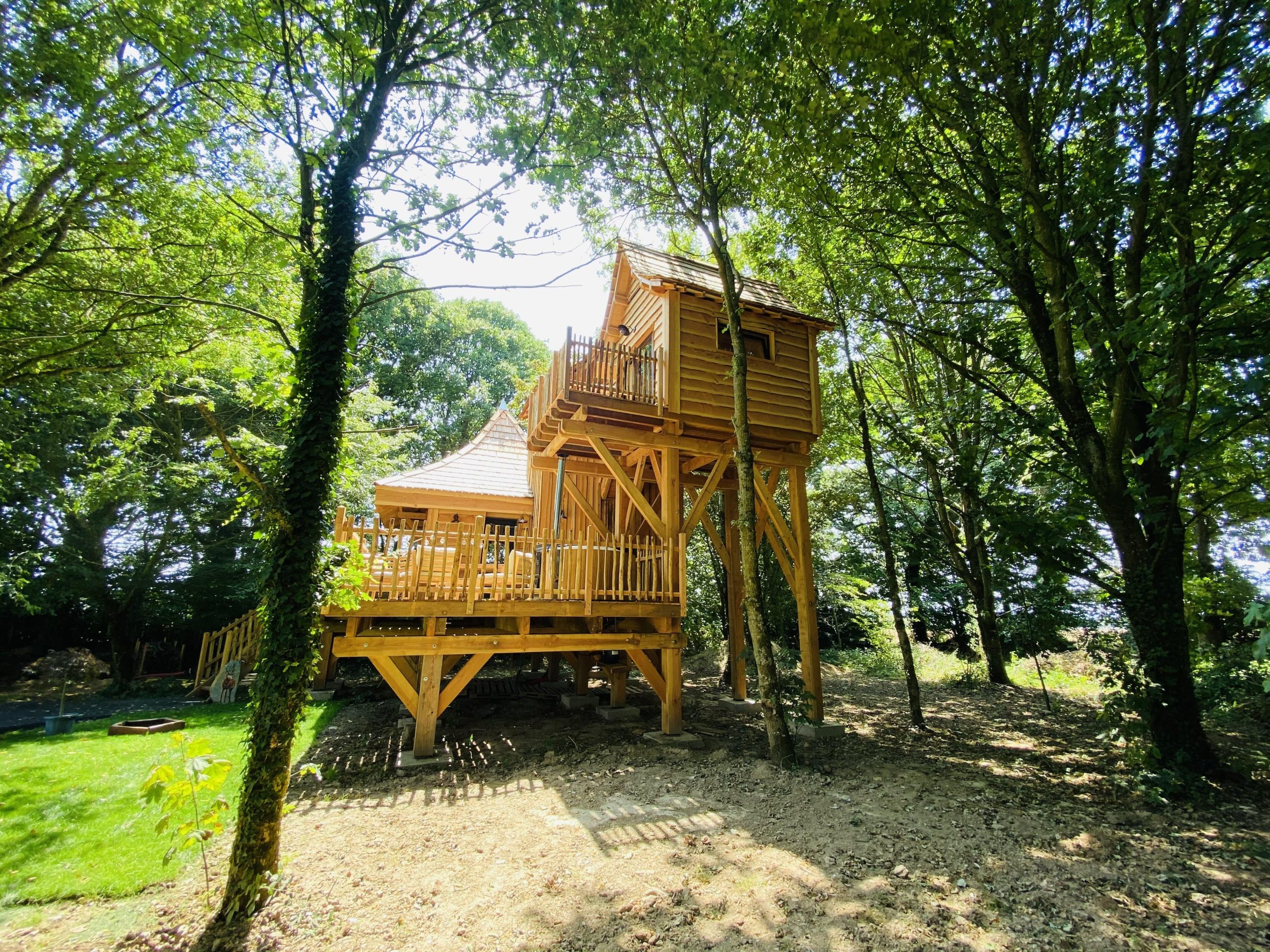 IMG_7969 Cabane perchée en bois, entourée darbres, offrant une vue paisible sur la nature.