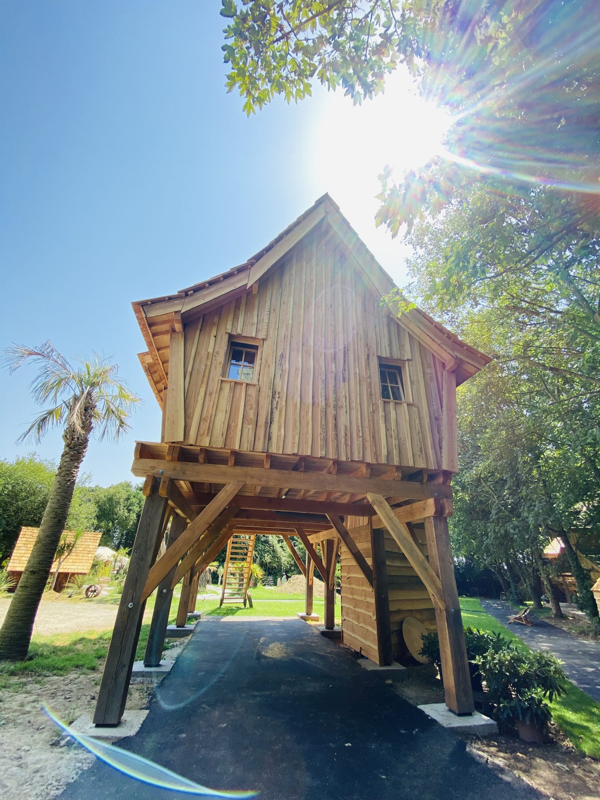 IMG_7973 Cabane sur pilotis en bois, baignée de lumière sous un ciel bleu en Bretagne.