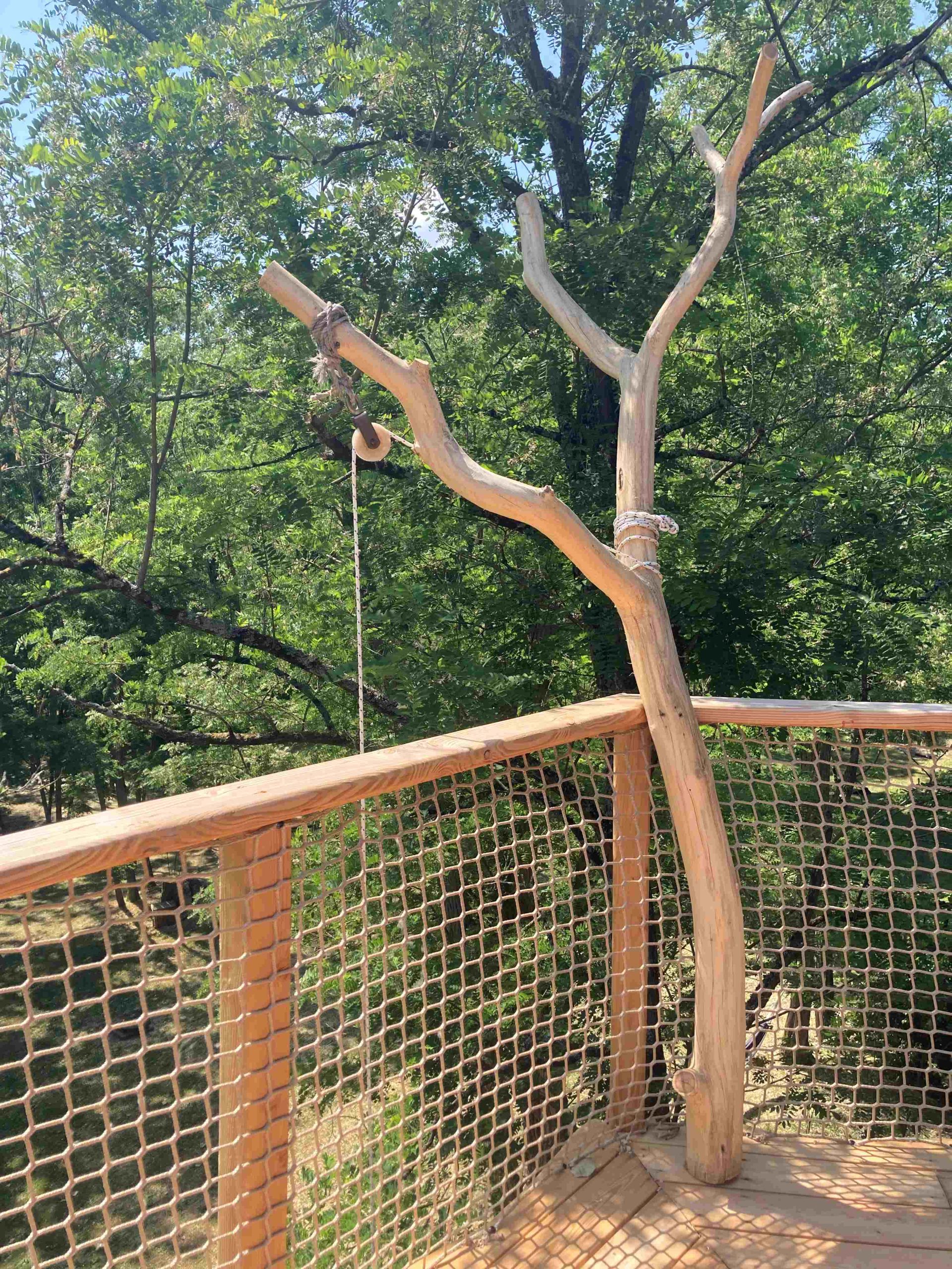 verger poulie Cabane perchée dans les arbres, avec un garde-corps en bois et une vue sur la nature.