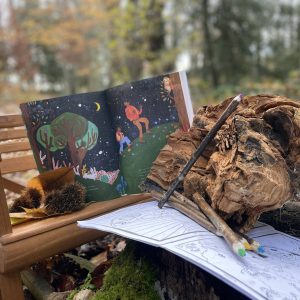 Cabane en bois au cœur de la nature, avec un livre illustré et des crayons.
