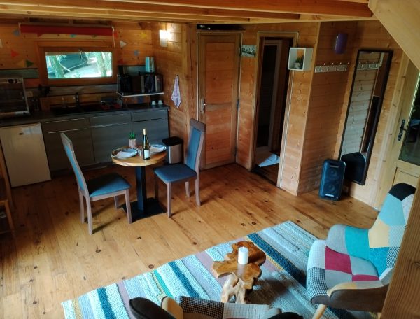 Cabane en bois à Aquitaine, intérieur chaleureux avec mobilier coloré et coin repas.