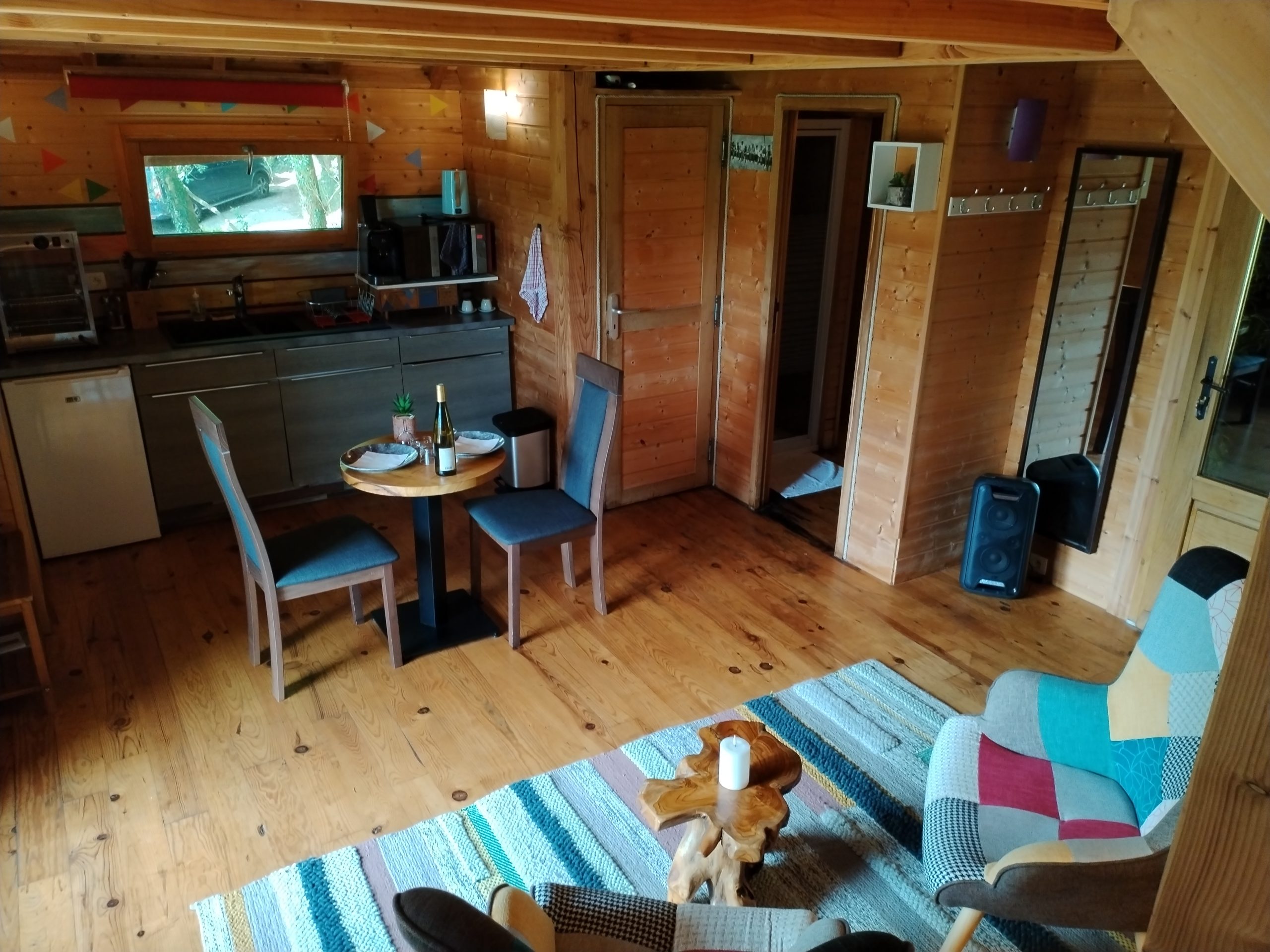 Cabane en bois à Aquitaine, intérieur chaleureux avec mobilier coloré et coin repas.