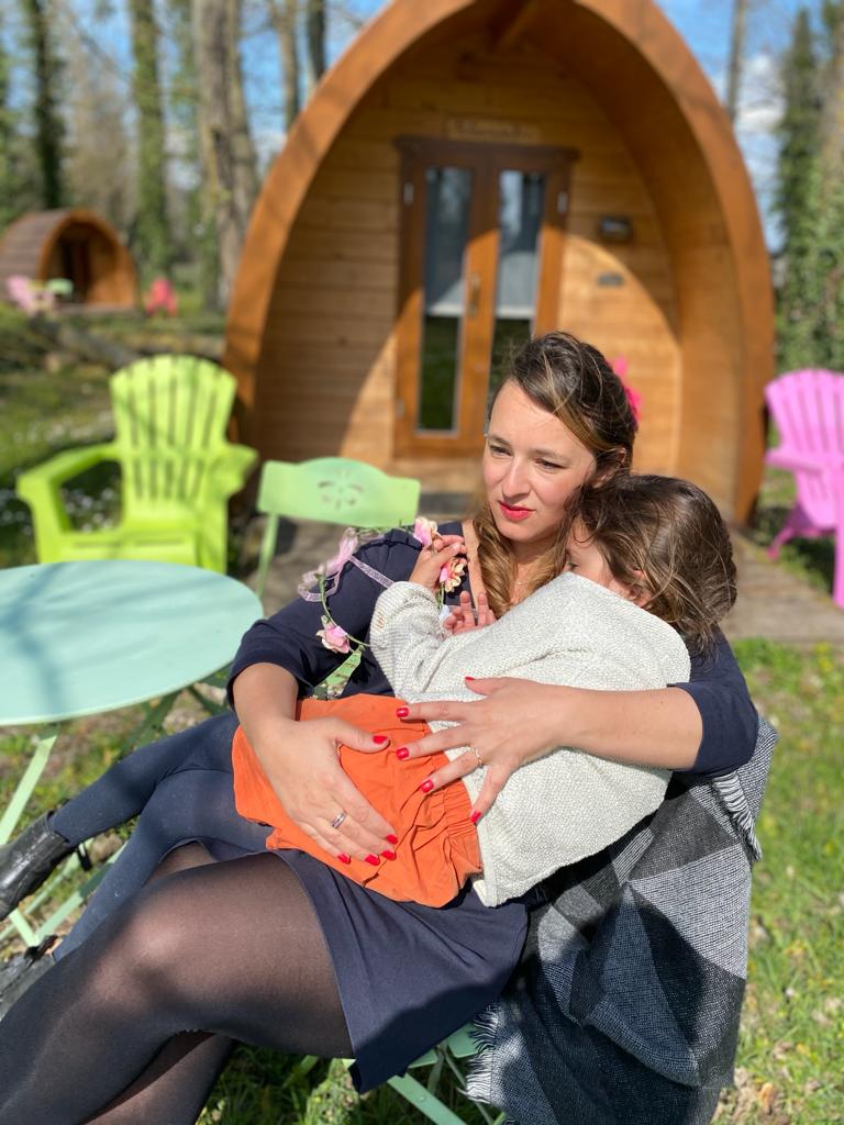 3d3063f6-600d-4708-a8e3-e015fac03ce7 Hébergement insolite en forme de cabane en bois, entouré de verdure et de chaises colorées.
