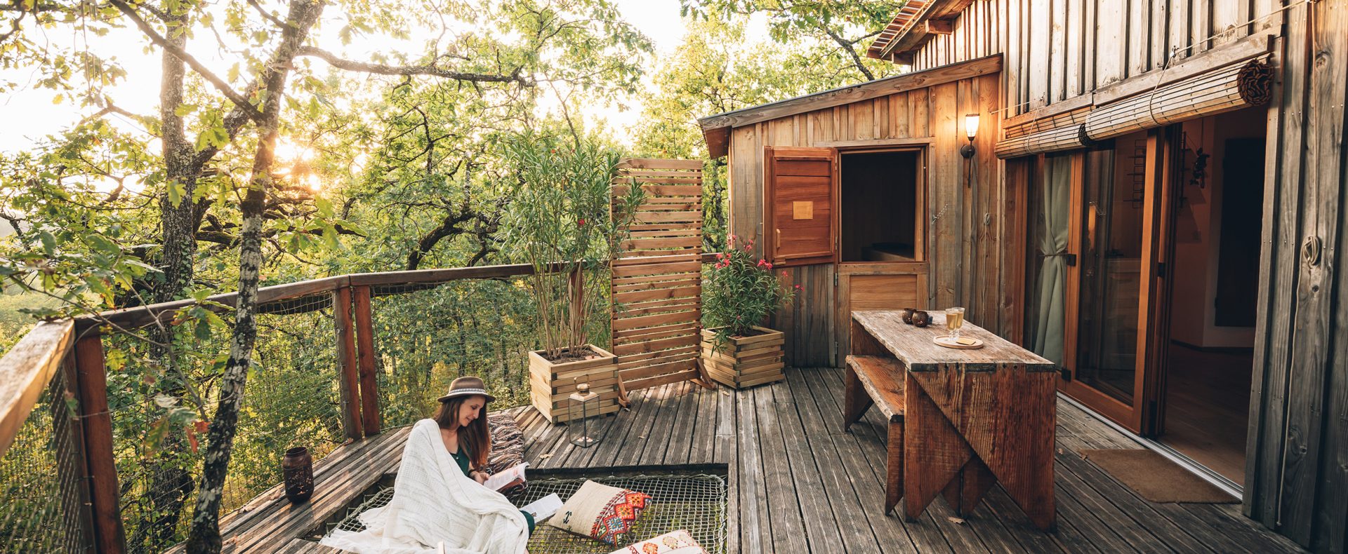 Cabane perchée en bois avec terrasse, ambiance cosy au milieu des arbres.