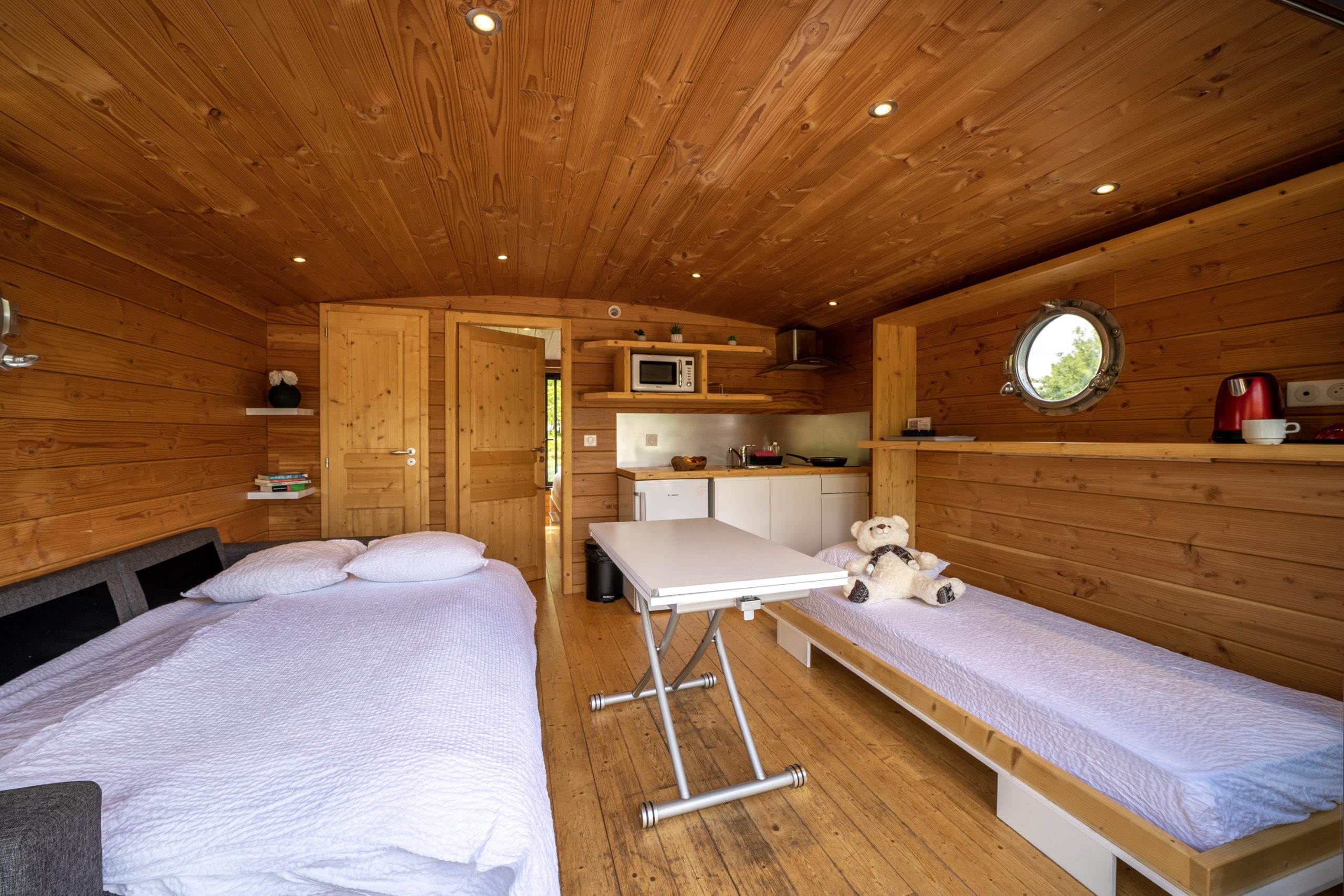 Chassenard_J1-45 Hébergement insolite en Auvergne : intérieur en bois chaleureux avec lits simples et cuisine.