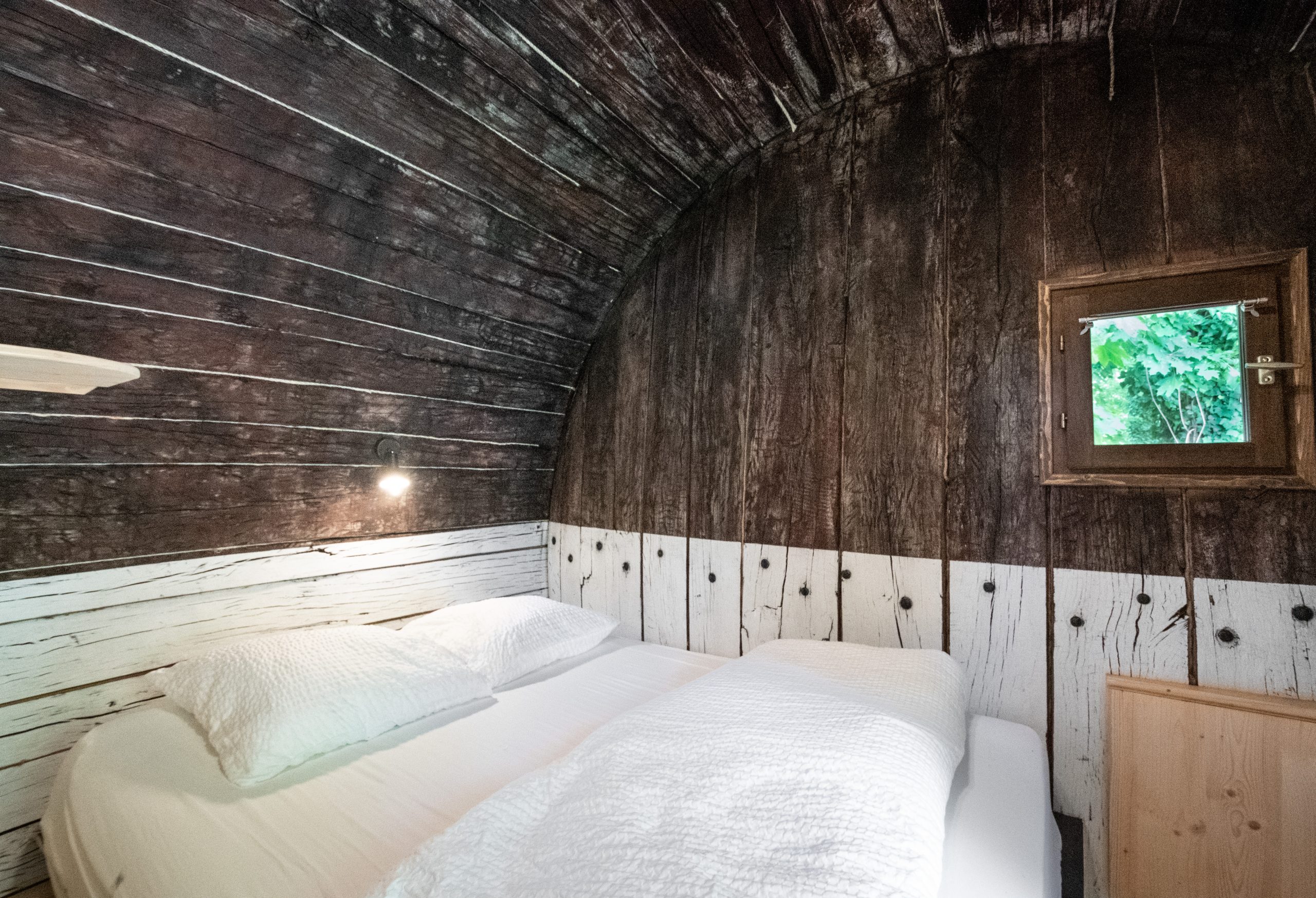 _DSC1236 Hébergement insolite en Auvergne : cabane en bois avec lit confortable et fenêtre.