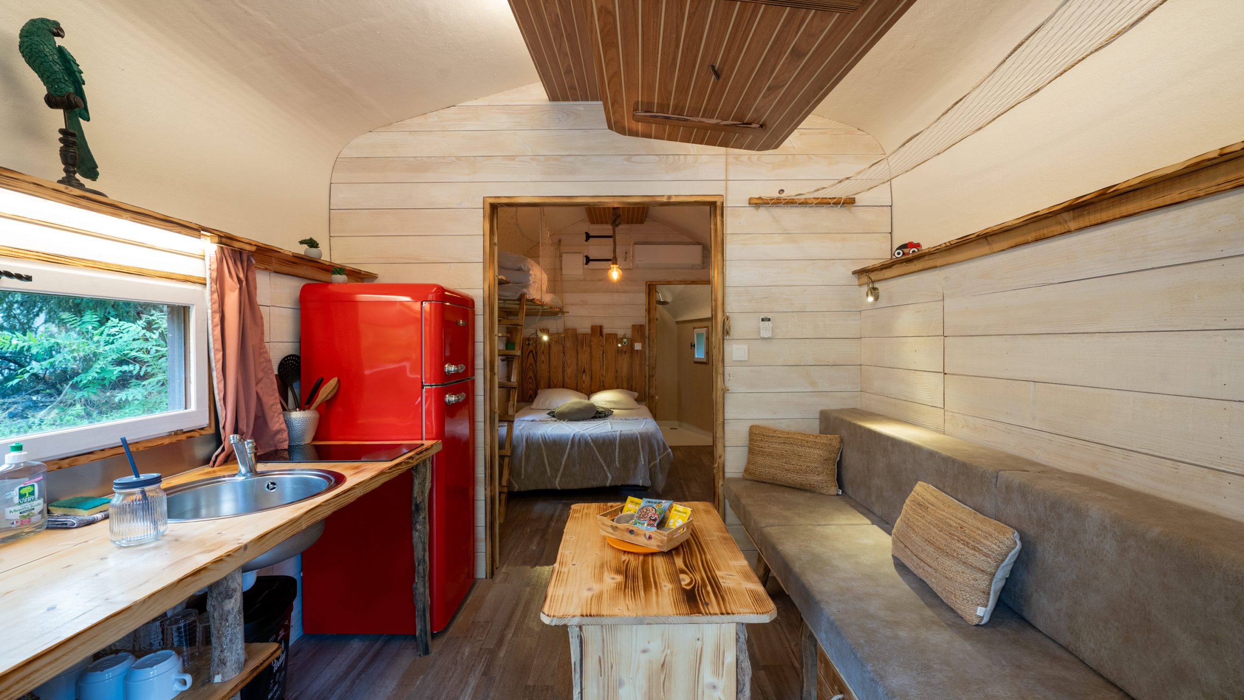 J5_6Champagne-1 Cabane en bois à Champagne-Ardenne, avec un intérieur chaleureux et un frigo rouge vintage.