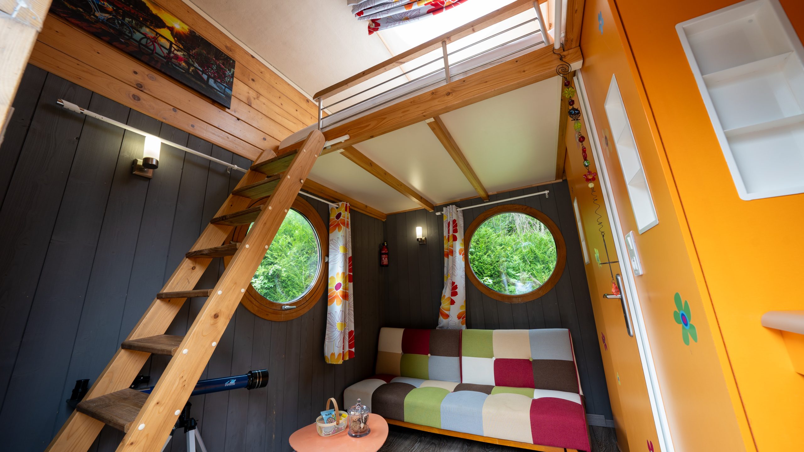 J5_6Champagne-47 Cabane insolite à Champagne-Ardenne, avec un intérieur coloré et des fenêtres rondes.