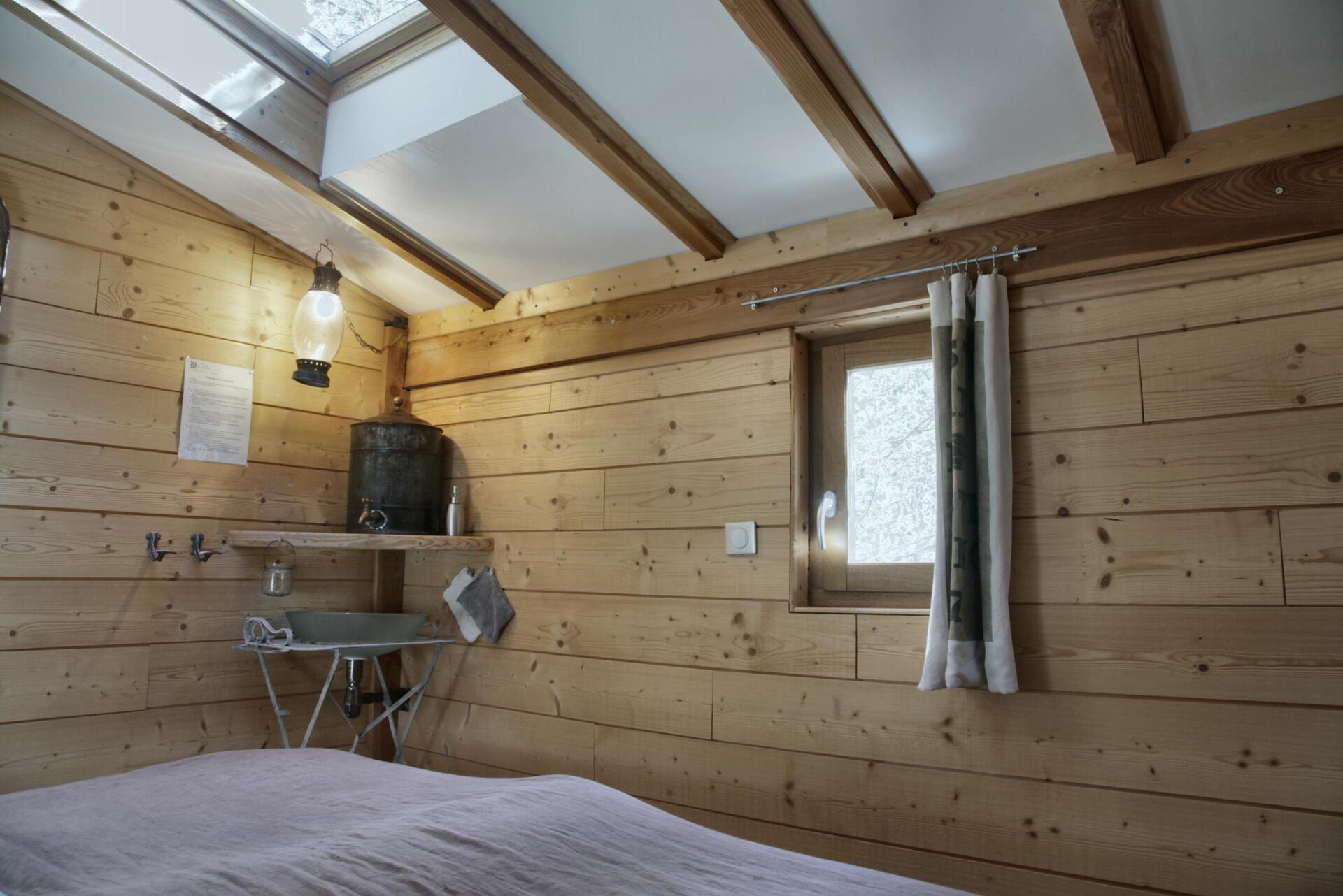 ©TerredesBaronnies-Cabane Pégase-Chambre-Hautes-Alpes Cabane en bois chaleureuse avec poutres apparentes et lumière naturelle.
