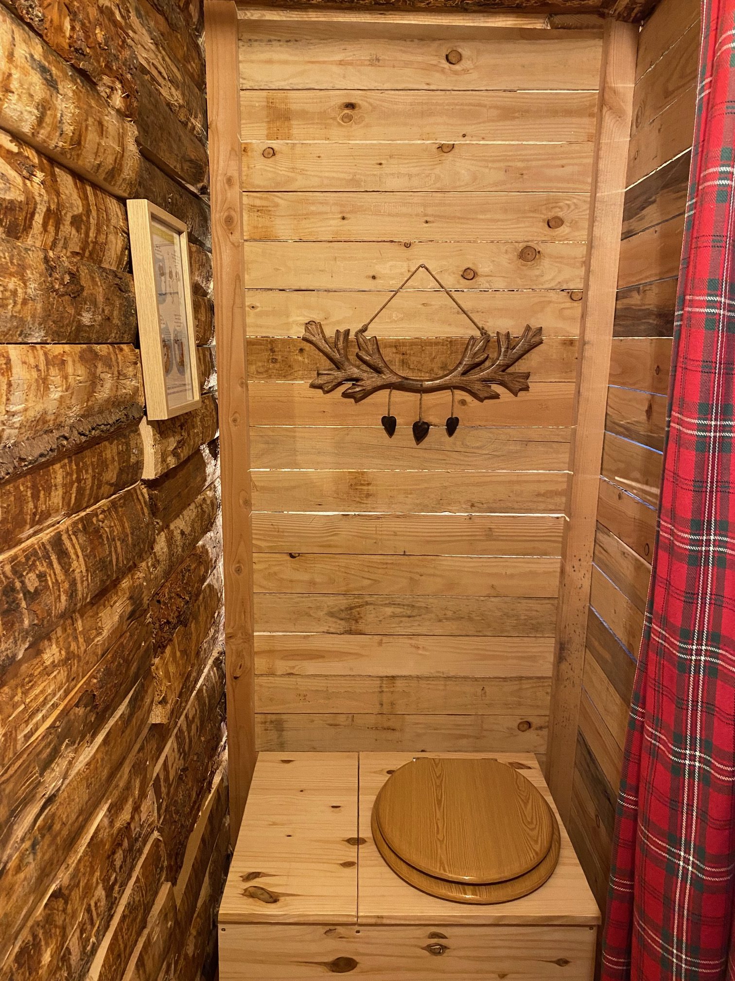 IMG_8690+ Cabane en bois avec toilettes en bois, décor rustique et ambiance chaleureuse.
