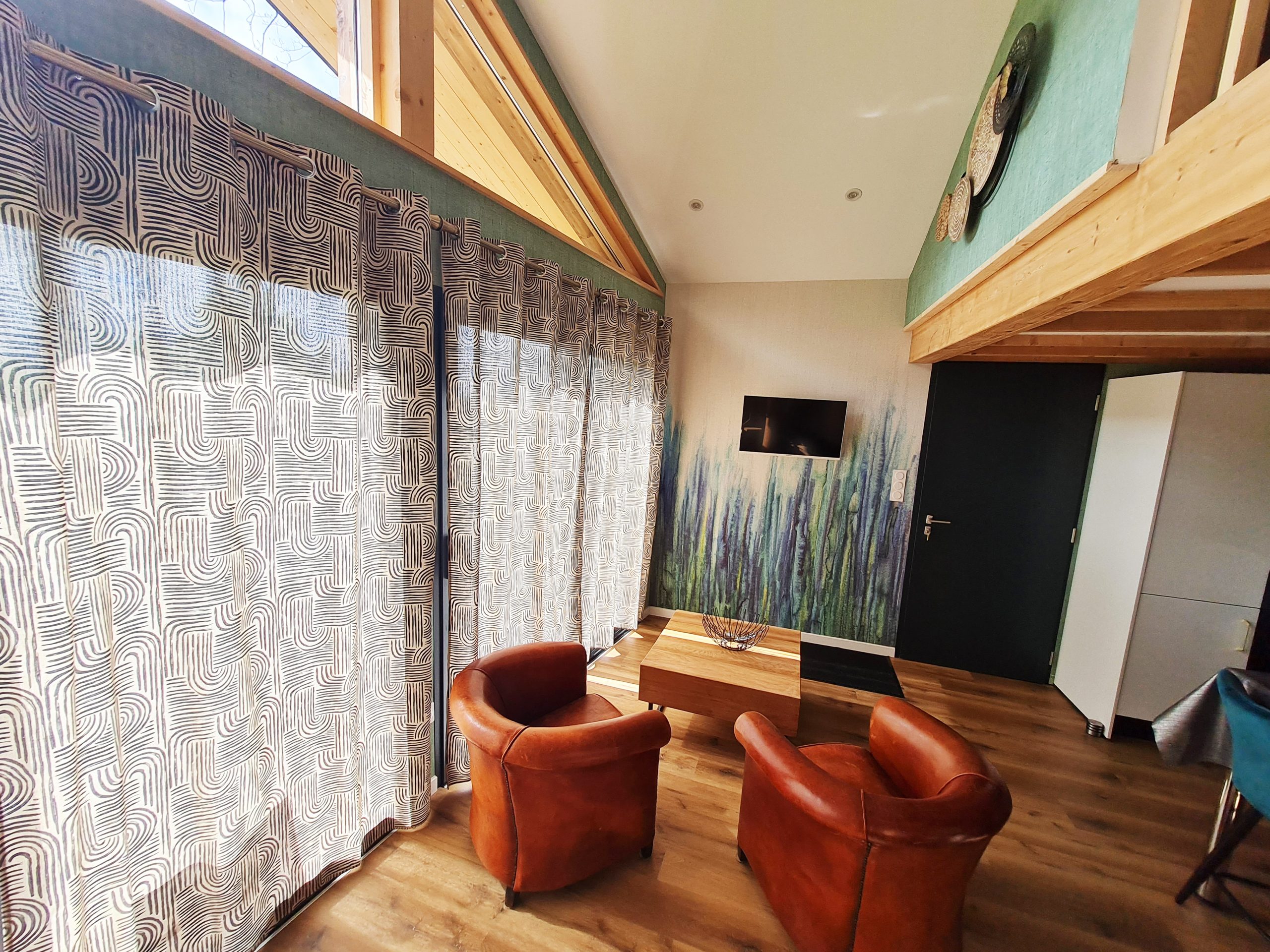 piece-de-vie Hébergement insolite en Bourgogne-Franche-Comté avec salon lumineux et fauteuils en cuir.