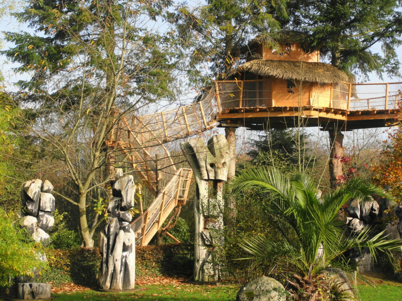 DSC01635-1-scaled-e1627464478993 Cabane dans les arbres en Bretagne, entourée de sculptures en bois et verdure luxuriante.