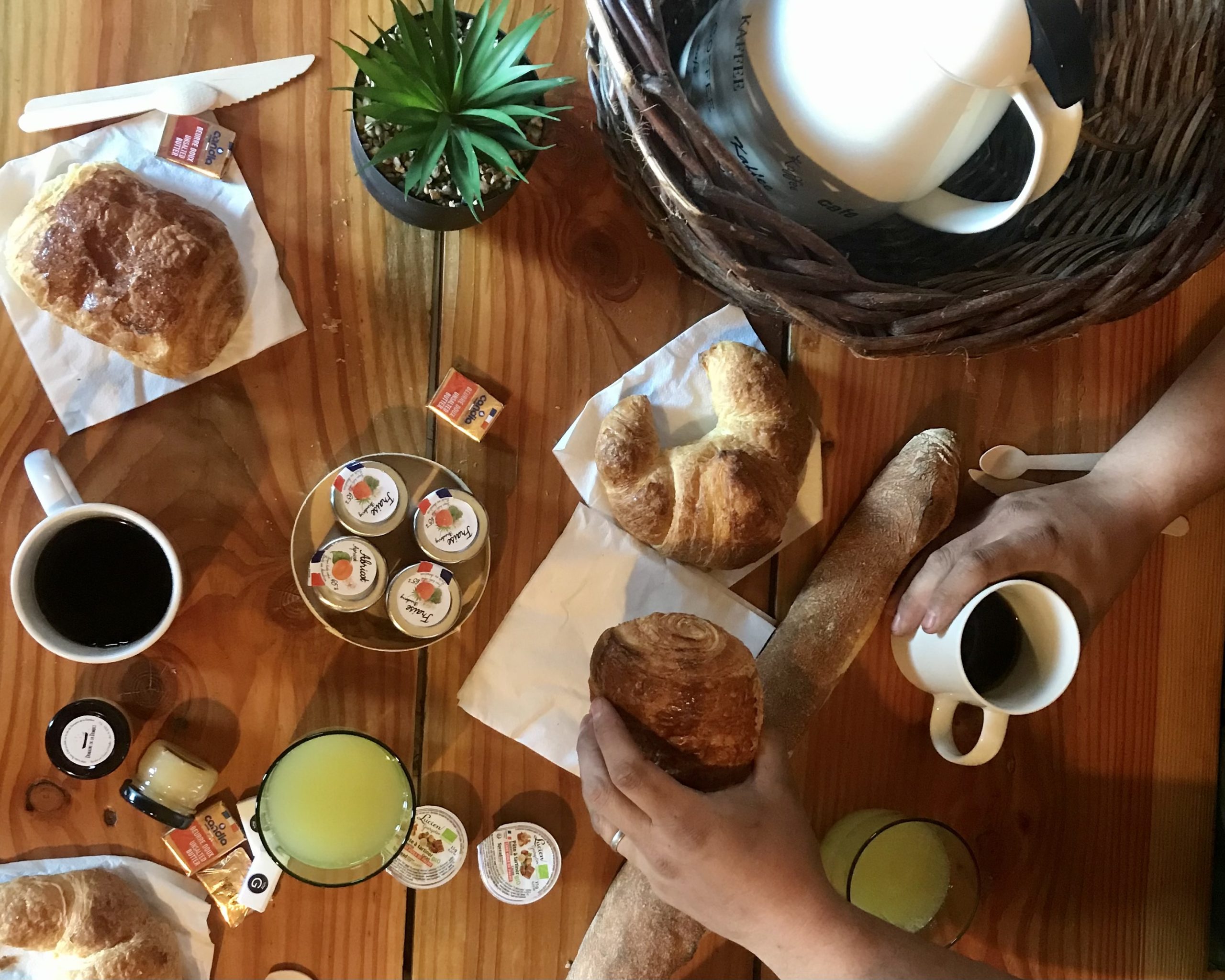 IMG_3415 Petit-déjeuner convivial dans un gîte en bois, avec croissants et café sur table en bois.
