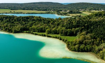Hébergement en pleine nature avec vue panoramique sur un lac turquoise et des collines verdoyantes.