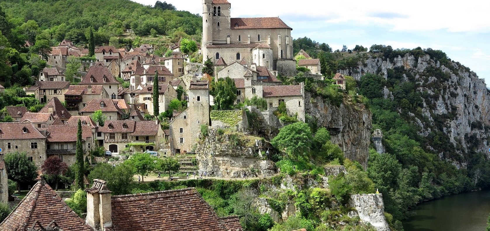 Charmant village médiéval avec des maisons en pierre et une église surplombant la rivière.