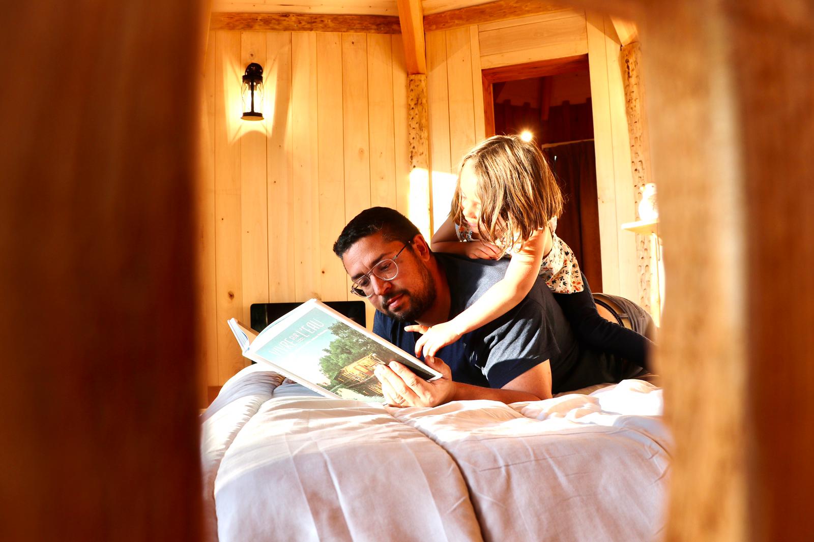 ea9fc4eb-1c56-4b2f-913a-678b2ff6f329 Hébergement insolite en bois en Auvergne-Rhône-Alpes, père et fille lisent ensemble.