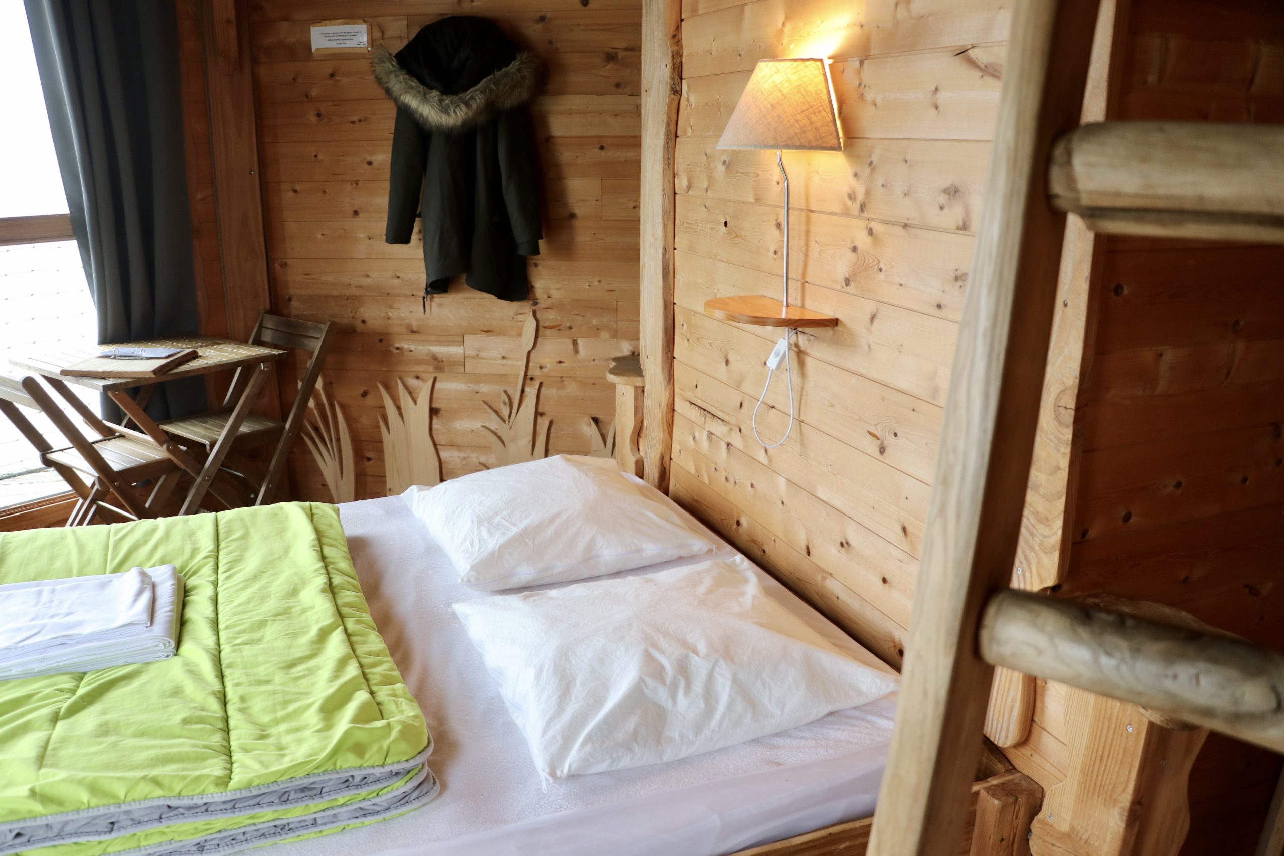 image_6487327 Chalet en bois chaleureux avec lit confortable et décoration naturelle.