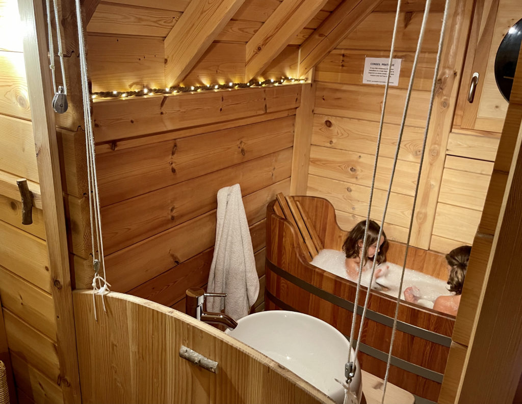 sangliers3 Cabane en bois avec baignoire en bois, ambiance chaleureuse et lumineuse.