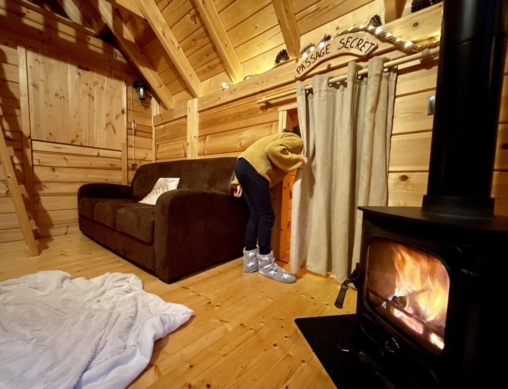 sangliers4 Cabane en bois avec un coin salon chaleureux et un poêle à bois accueillant.