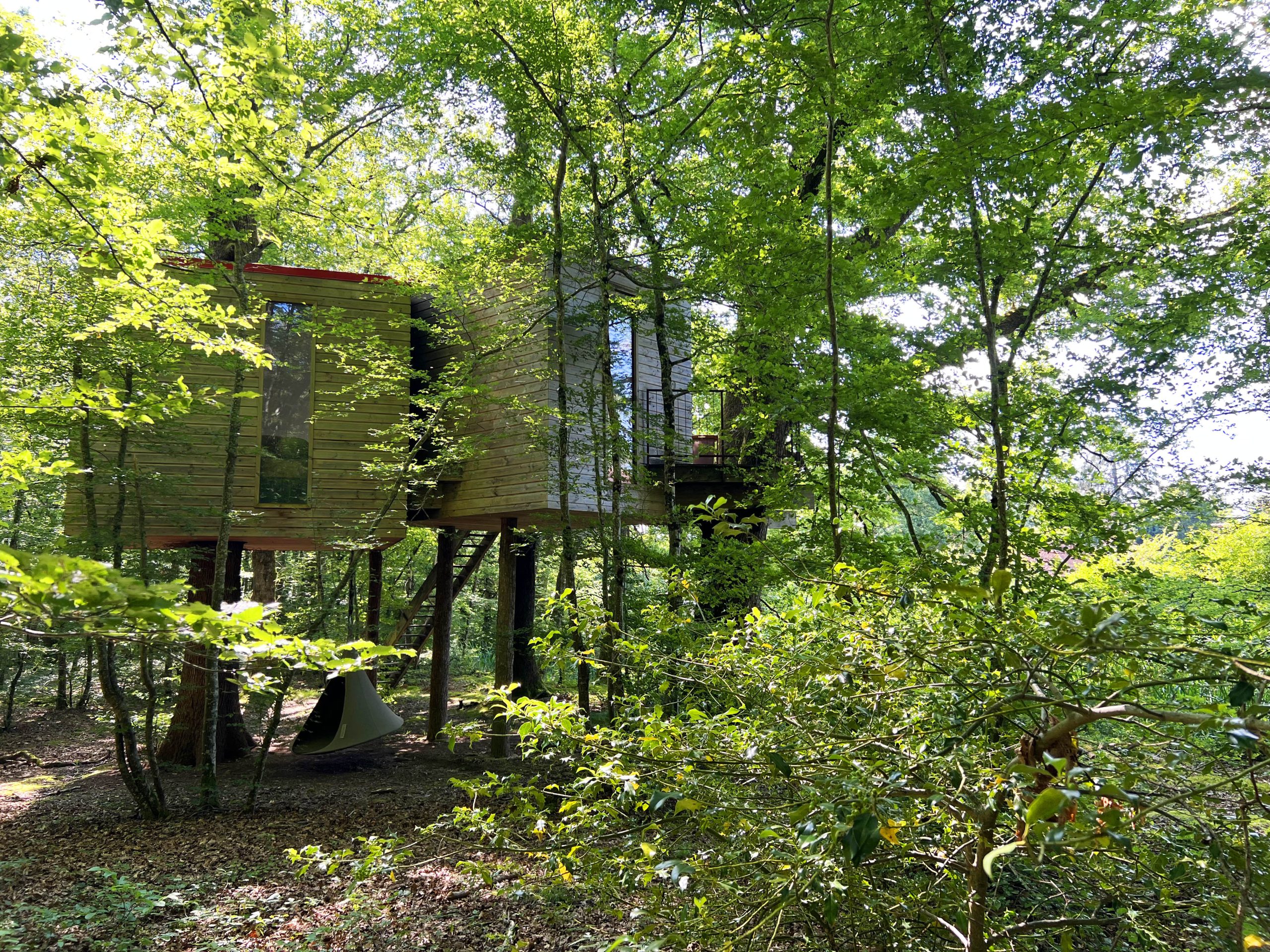 Eau1 Cabane perchée en bois, entourée darbres verdoyants en Bourgogne.