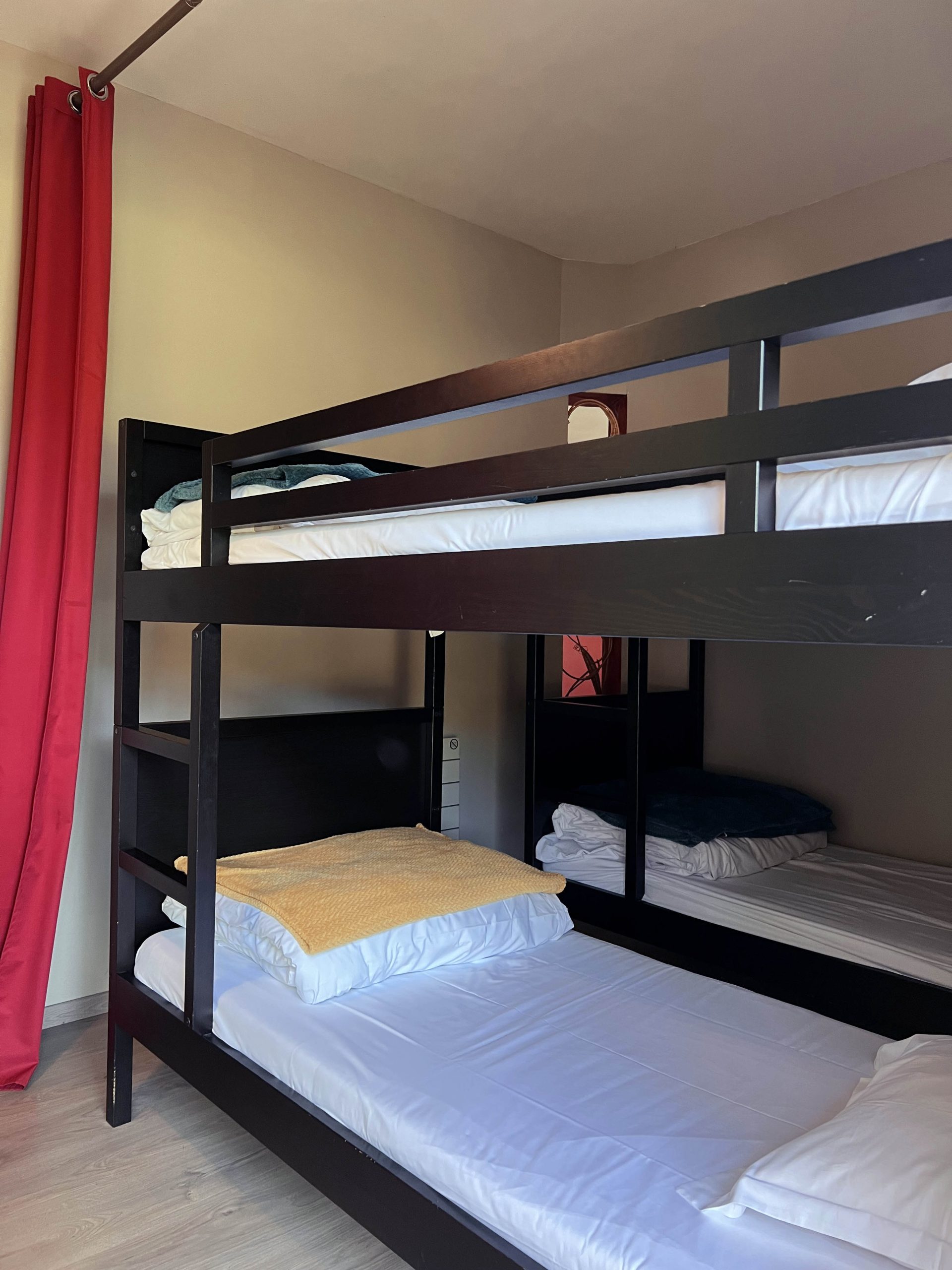 Eau3 Chambre partagée avec lits superposés, murs clairs et rideaux rouges en Bourgogne.