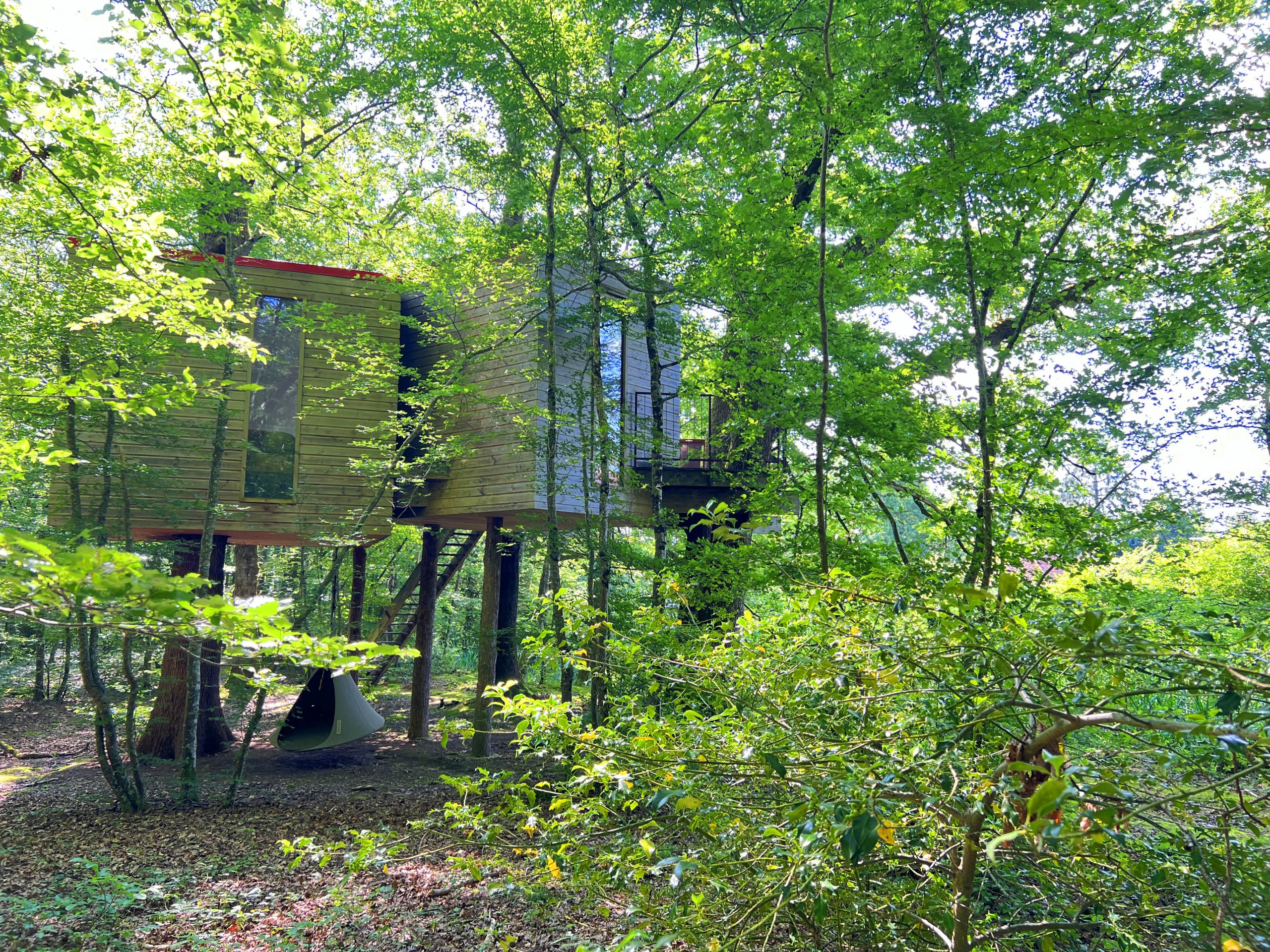 Eau9 Cabane perchée en bois, entourée de verdure luxuriante en Bourgogne.