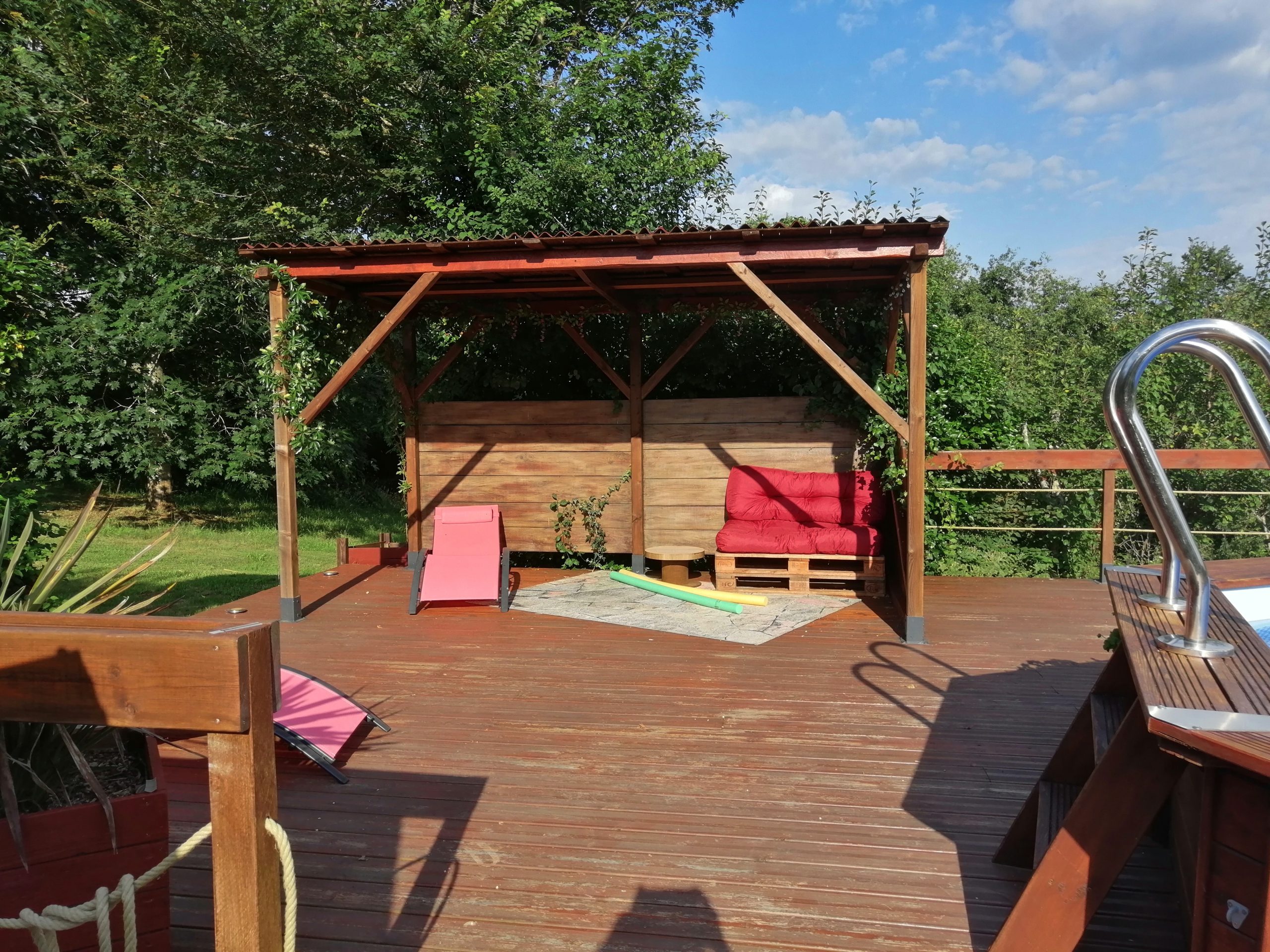 IMG_20240711_091220 Hébergement insolite en Midi-Pyrénées : terrasse en bois avec transats colorés et ombre.