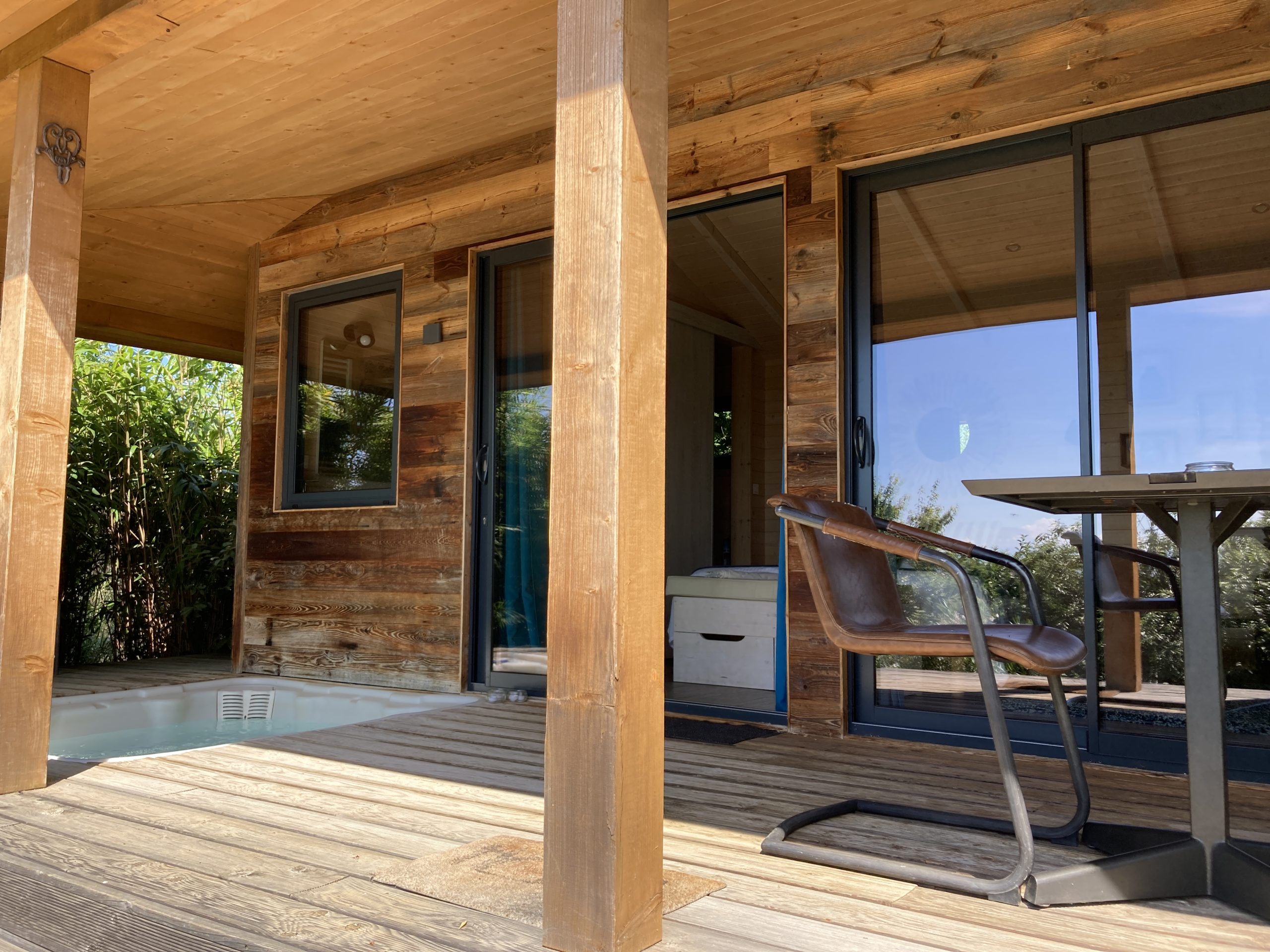 IMG_4402 Cabane en bois avec terrasse et jacuzzi, entourée de verdure à Languedoc-Roussillon.