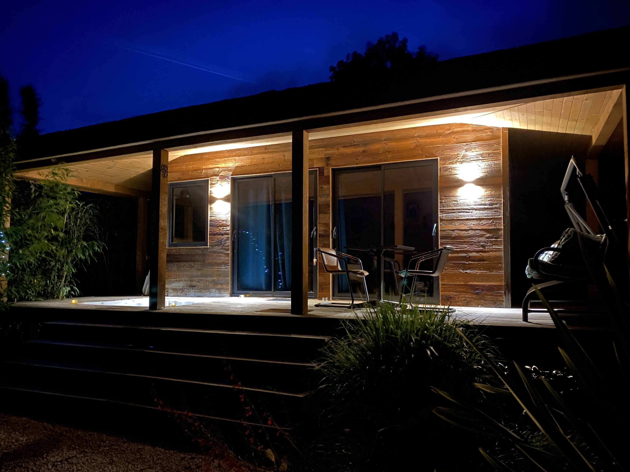 IMG_6353 Cabane en bois illuminée la nuit, offrant une ambiance chaleureuse et accueillante.