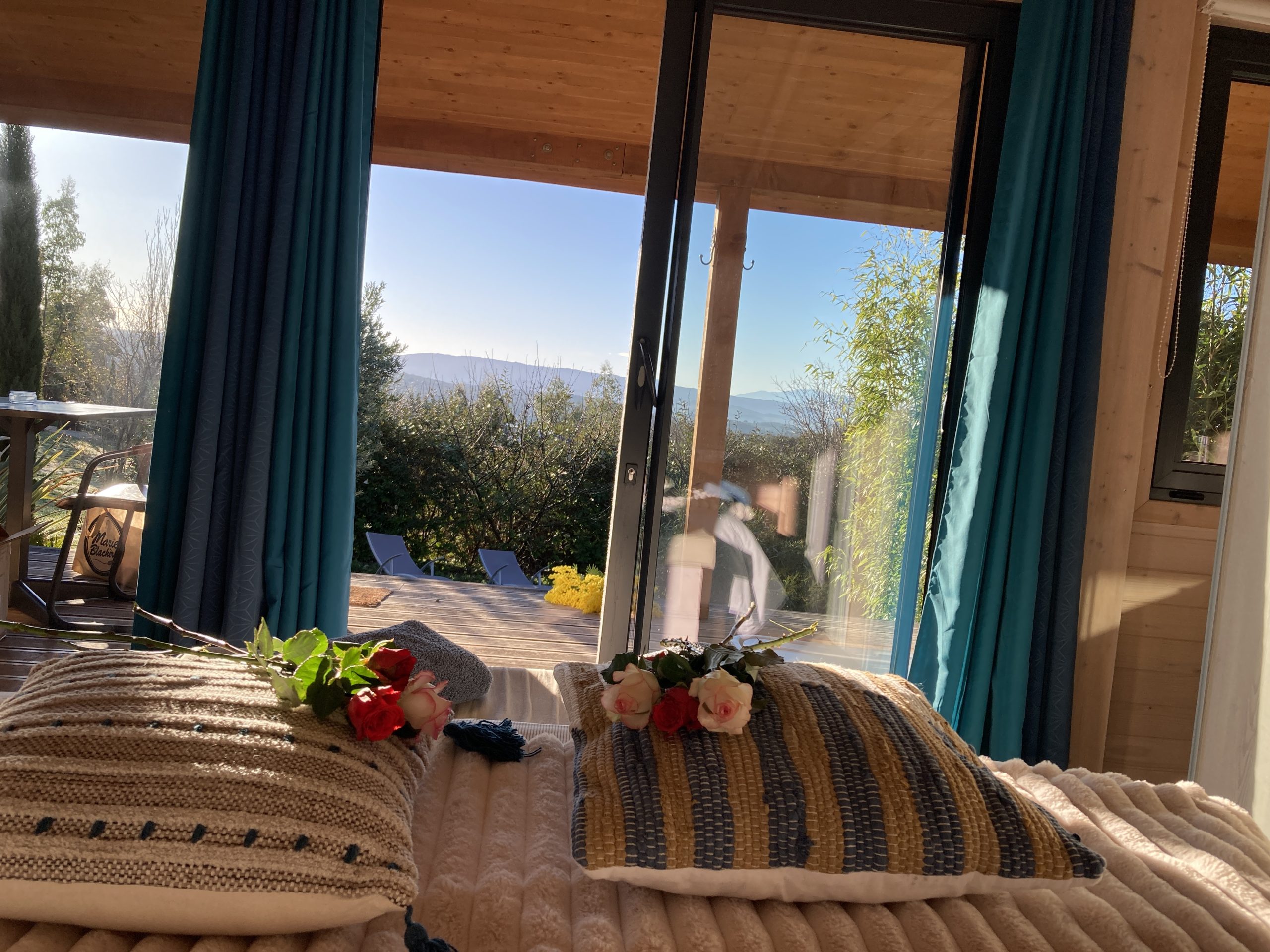 Le jour se lève Cabane des Baies sauvages Chalet en bois avec vue sur la nature, décoré de coussins et fleurs.