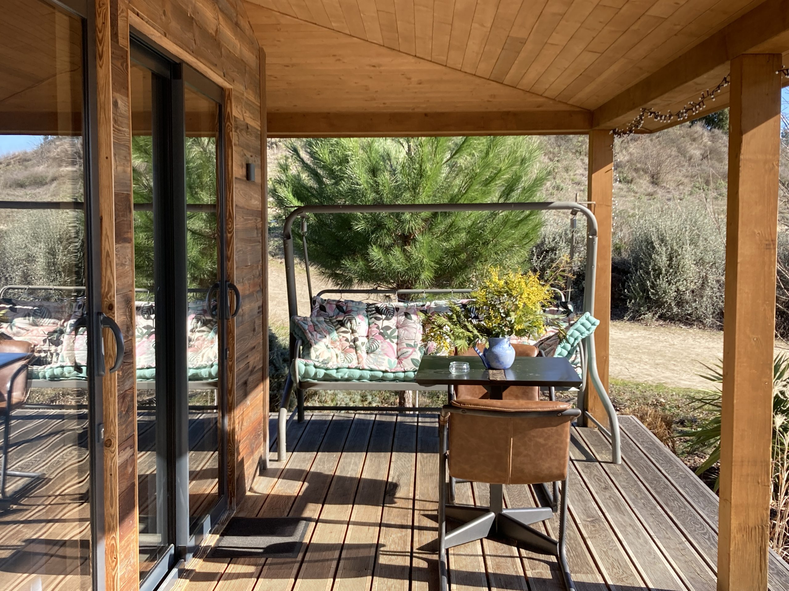 terrasse et balancelle Cabane des Baies sauvages Cabane en bois avec terrasse, fauteuils confortables et vue sur la nature environnante.