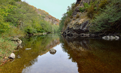 Hébergement en bord de rivière, entouré de falaises verdoyantes et dune eau cristalline.