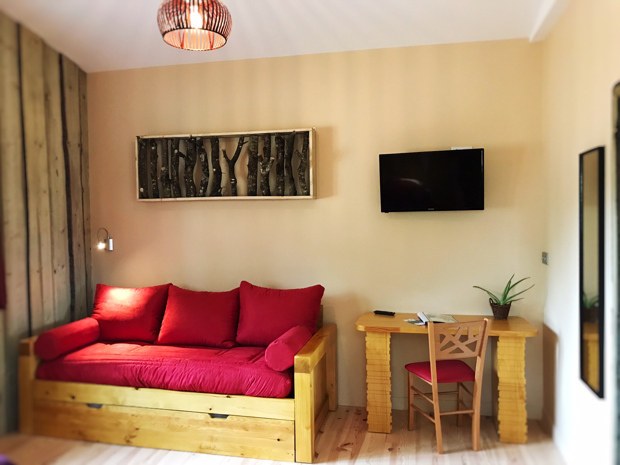 banquette Hébergement insolite en Nouvelle-Aquitaine : salon cosy avec canapé rouge et table en bois.