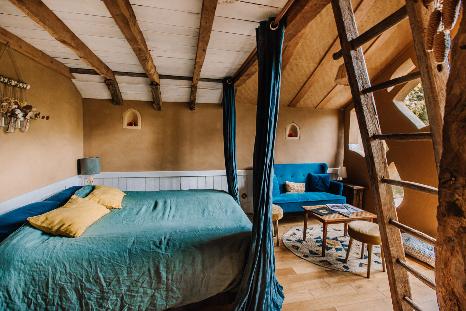 intérieur chambre Hébergement insolite en Bretagne : chambre chaleureuse avec lit douillet et poutres apparentes.