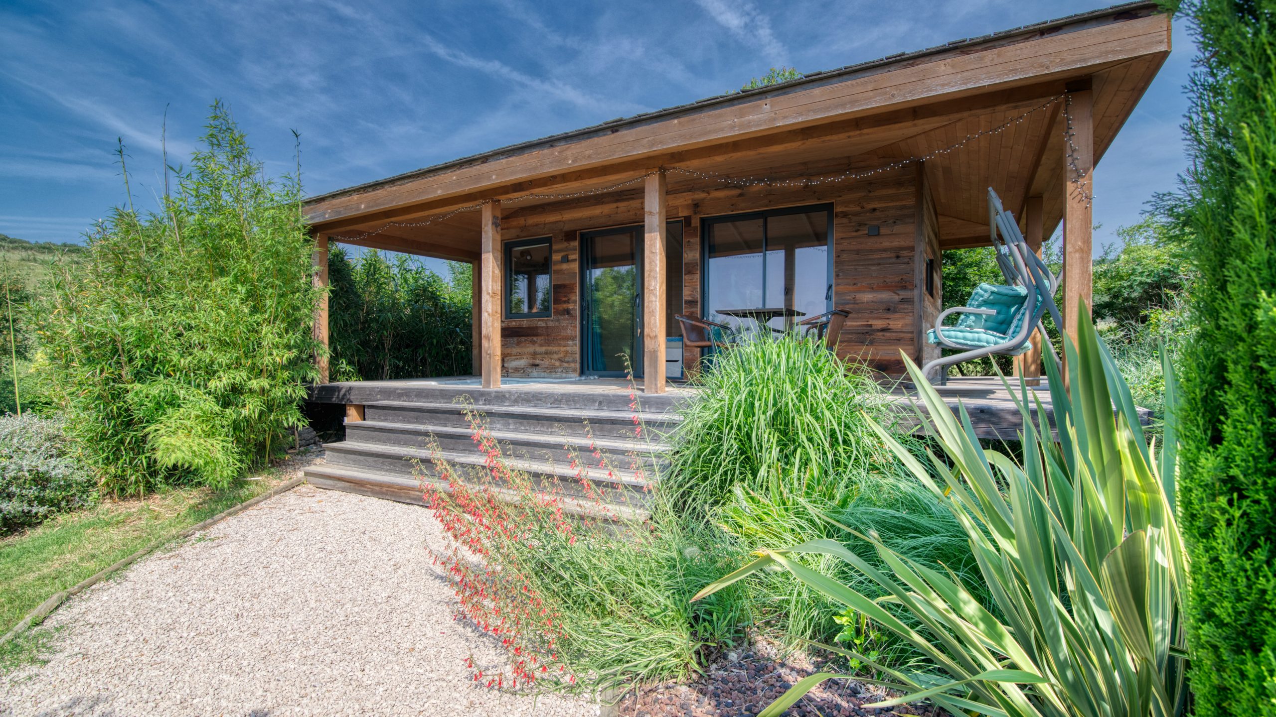 Cabane des Baies sauvages Cabane en bois avec terrasse, entourée de verdure luxuriante à Languedoc-Roussillon.