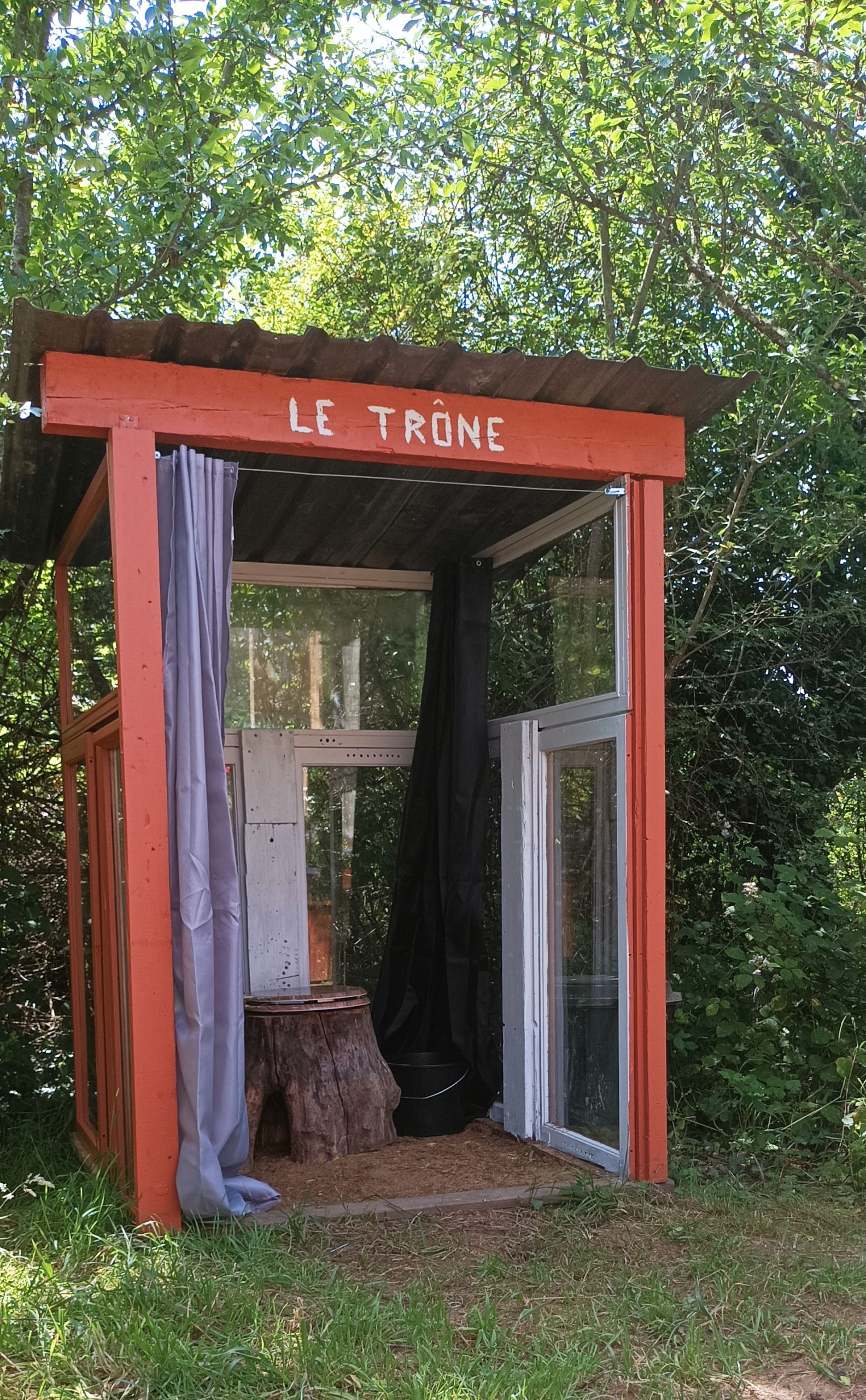 cabane du rêveur - estivale (10) Hébergement insolite Le Trône en bois, avec des fenêtres et un décor naturel verdoyant.